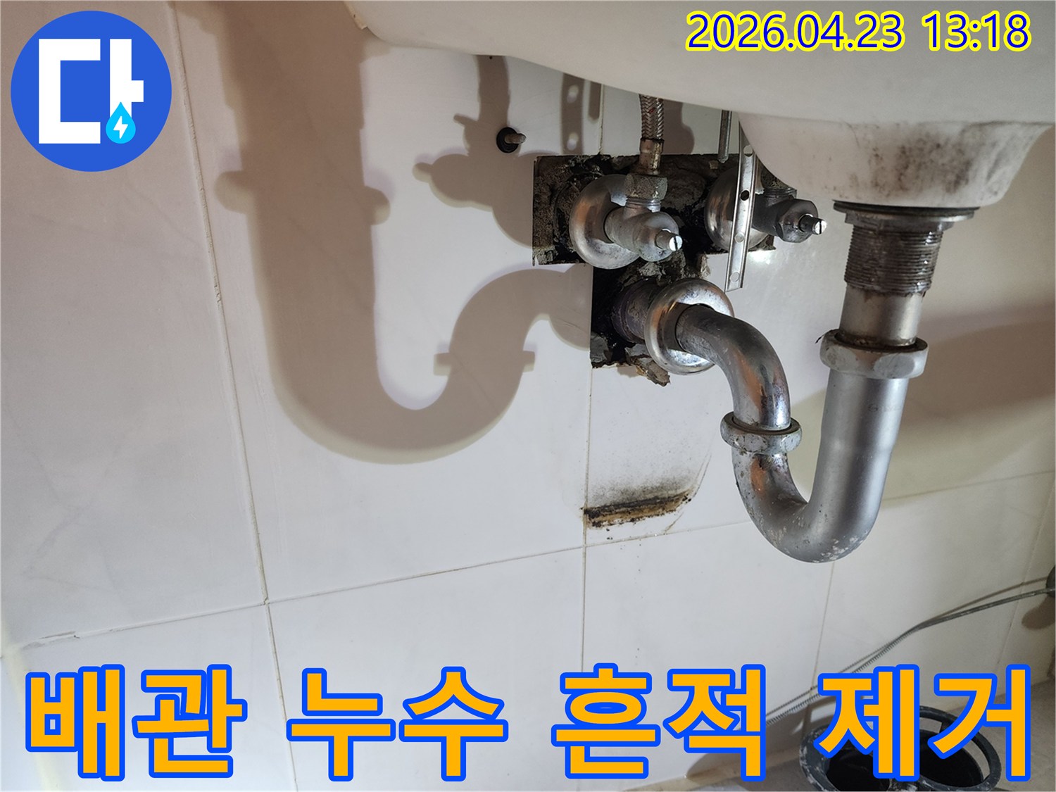 이 이미지는 양주 삼숭동 아파트 화장실 세면대 배관에서 발생한-누수로 인해 벽면에 생긴 물자국과 곰팡이 흔적을 보여줍니다.