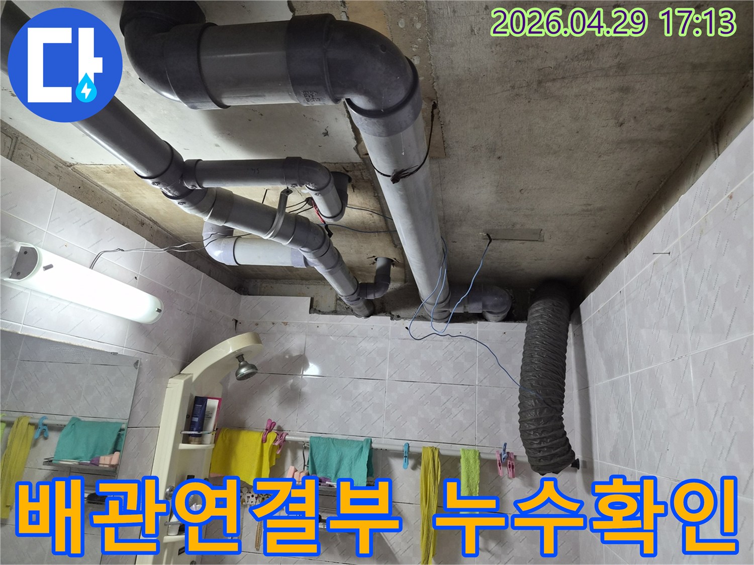 욕실 천장의 복잡한 배관 연결부에서-누수가 발생했는지 면밀히 확인하는 전문가의 모습입니다