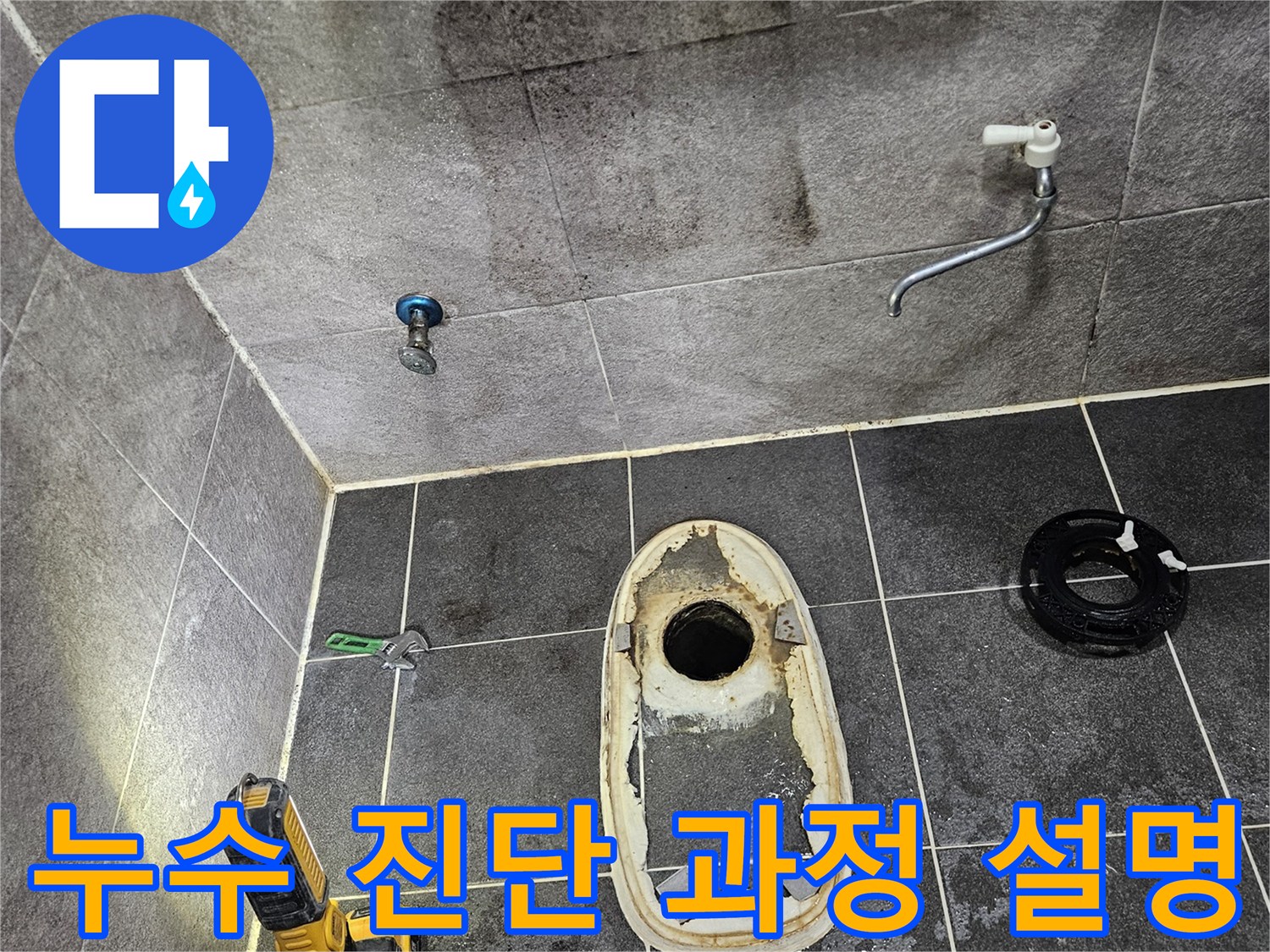 변기가 제거된 욕실 바닥의 누수 흔적을-손전등으로 밝히며-엔지니어가 고객에게 진단 과정을 설명하는 듯한 현장 모습입니다.