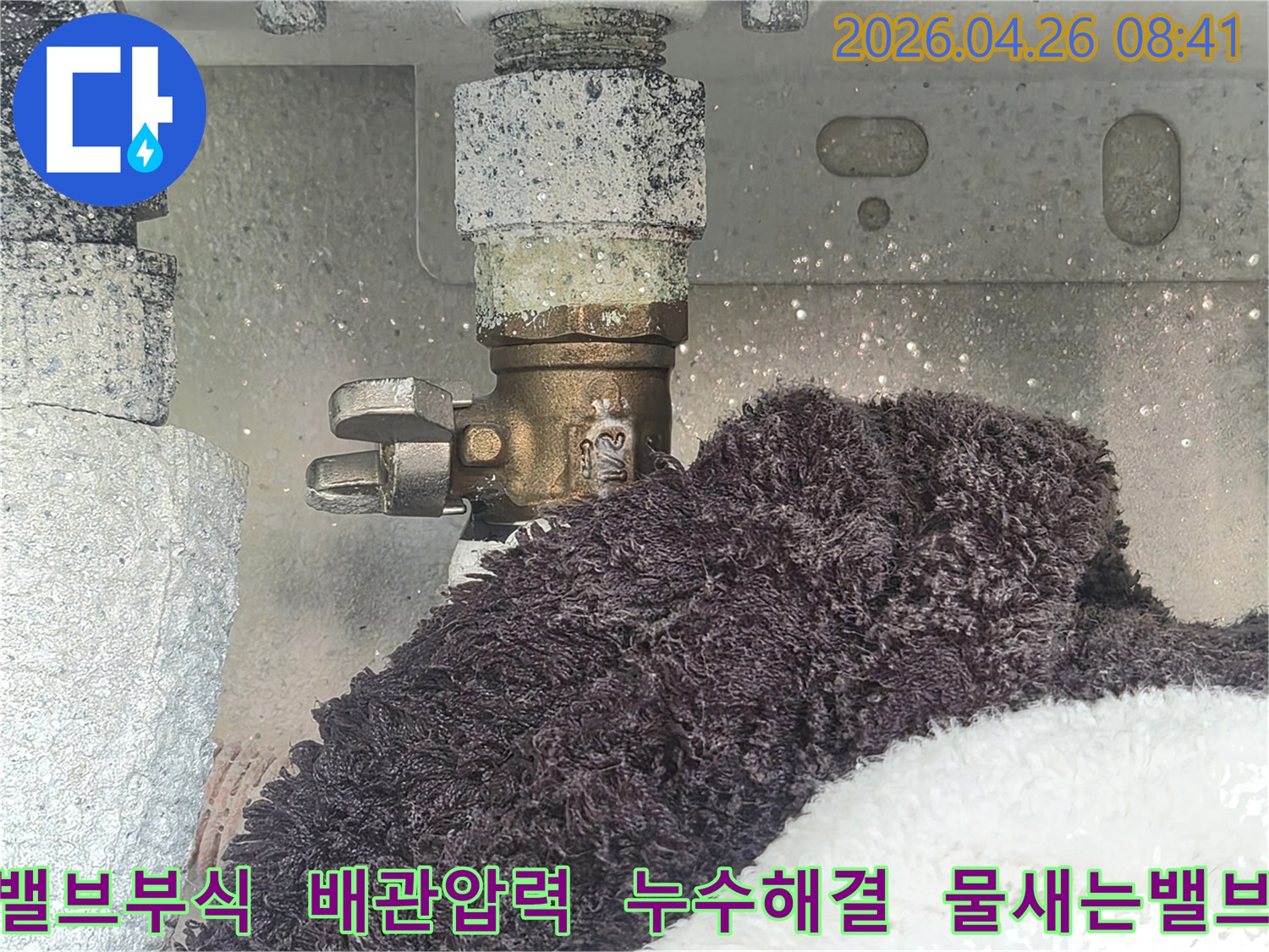 부식으로 인해 하얗게 변색된 수도 밸브에서 물이 새고 있는 현장-아래 수건이 젖어있는 모습-배관 압력 저하의 원인을 보여주는 이미지