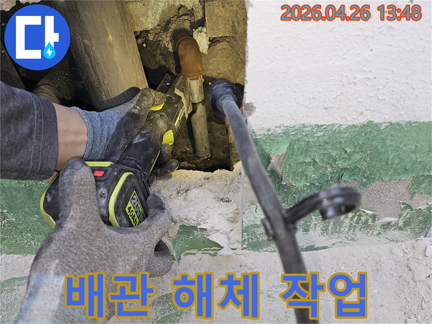 누수 전문 엔지니어가-벽 속에 숨겨진-손상된 배관을-전동 공구로-조심스럽게 잘라내고 있습니다.