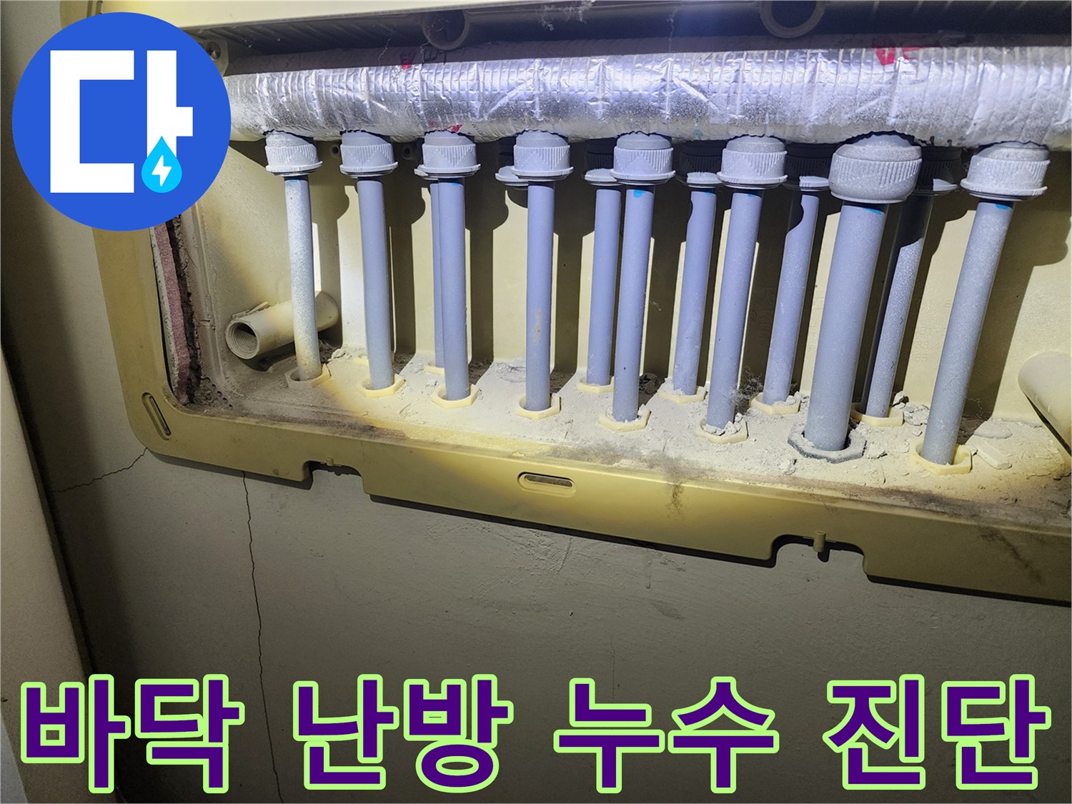 난방 분배기 하단에 위치한-배관 연결부에서 발생한-누수 흔적을-전문가가 정밀하게 확인하고 있습니다.