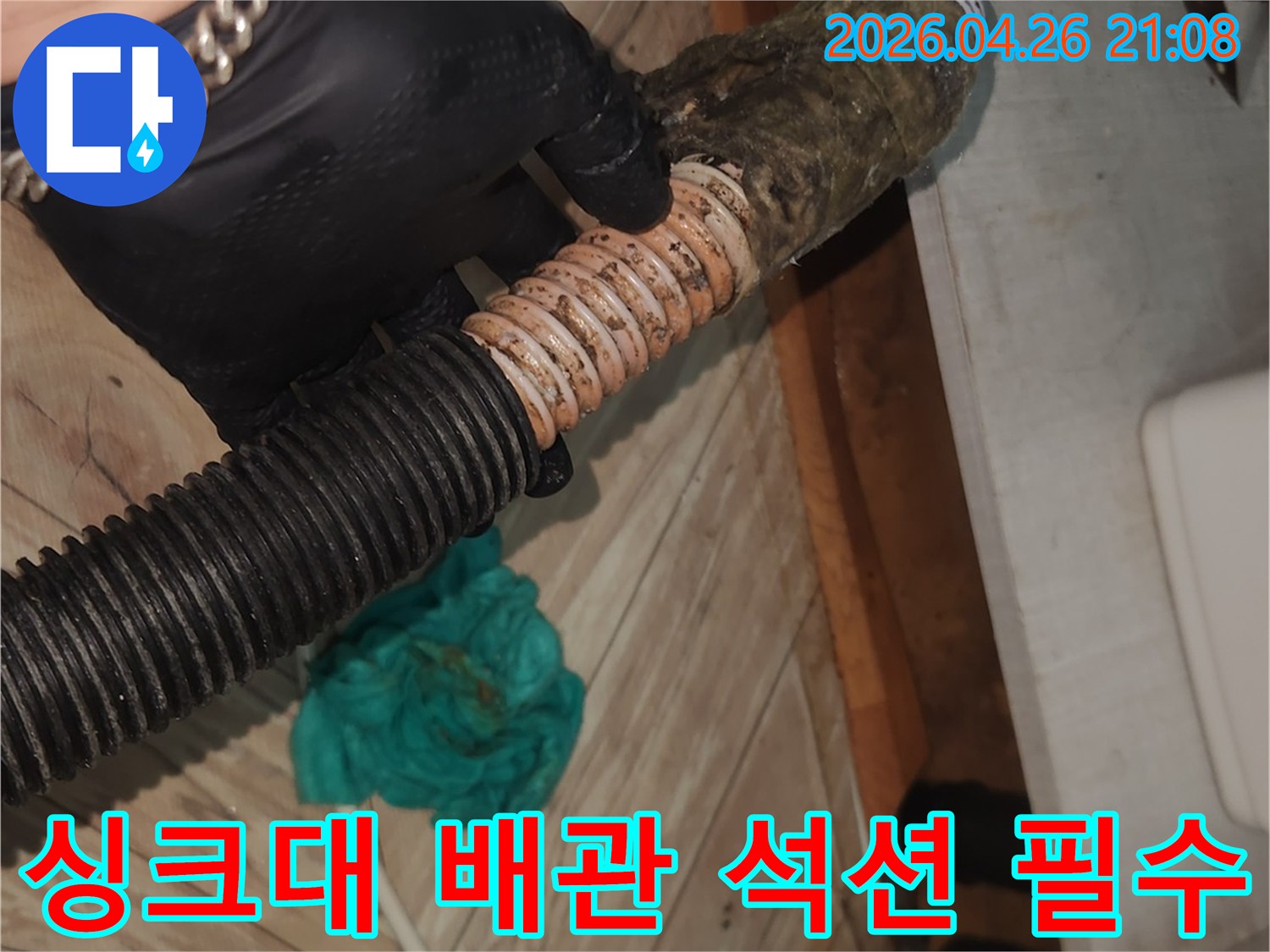 검은색 장갑을 낀 작업자가-오염된 싱크대 배수 호스를-석션 클리닝으로 꼼꼼하게 청소하는 중