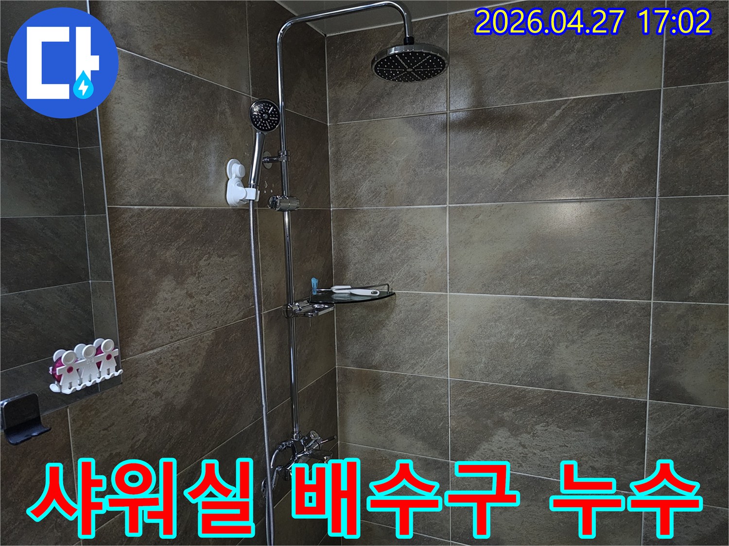 이 이미지는 욕실 샤워실의 바닥과 샤워기 설비를 보여주며-배수구 주변에서 발생할 수 있는 역류나 누수 문제를 점검하는 현장입니다.