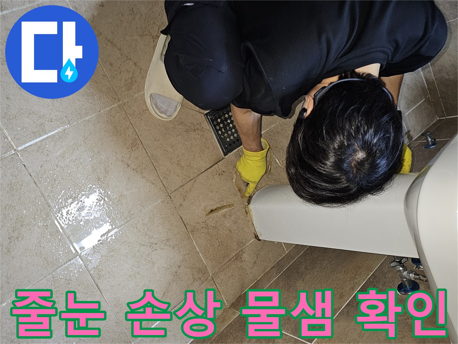전문 엔지니어가-노란 장갑을 끼고-욕실 바닥 타일의 젖은 줄눈과-그 주변을-손가락으로 가리키며-누수 지점을 면밀히 확인하는 장면