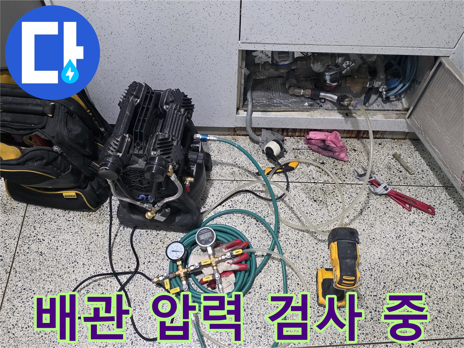 싱크대 하부 점검구 내부에 연결된 디지털 압력계와 공압 테스트 장비 모습