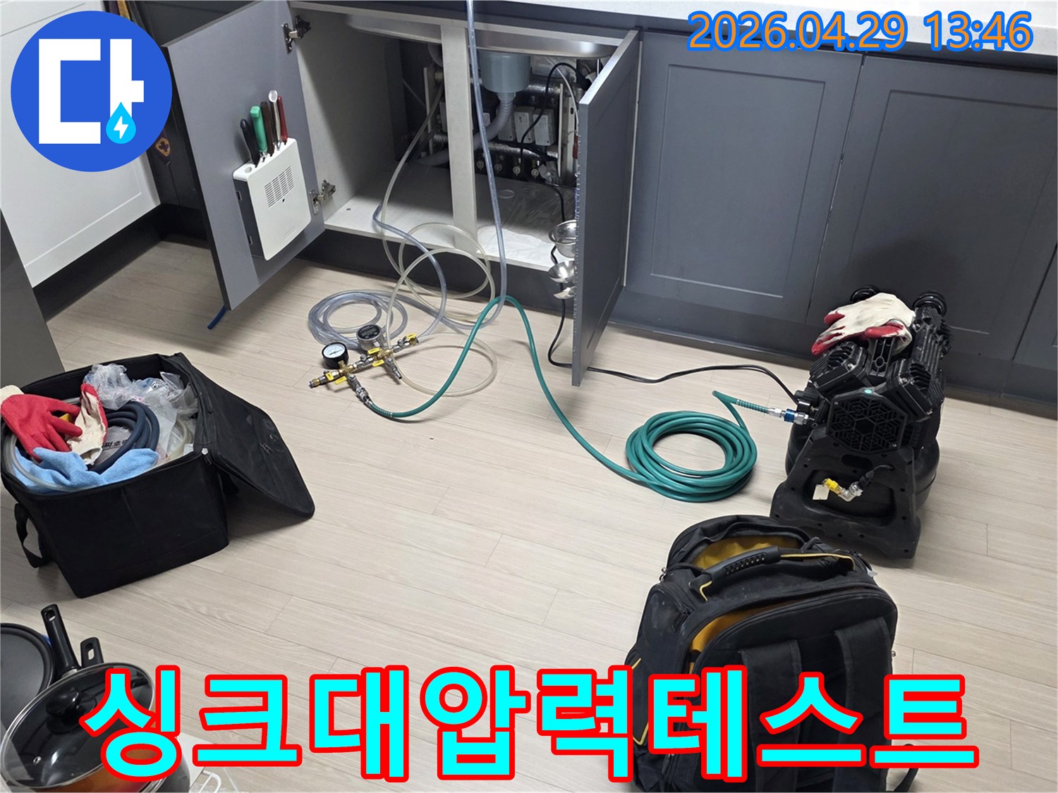아파트 주방 싱크대 하부에서-누수 확인을 위한-배관 압력 테스트 장비와-호스를 연결하여-테스트를 준비하는 모습입니다