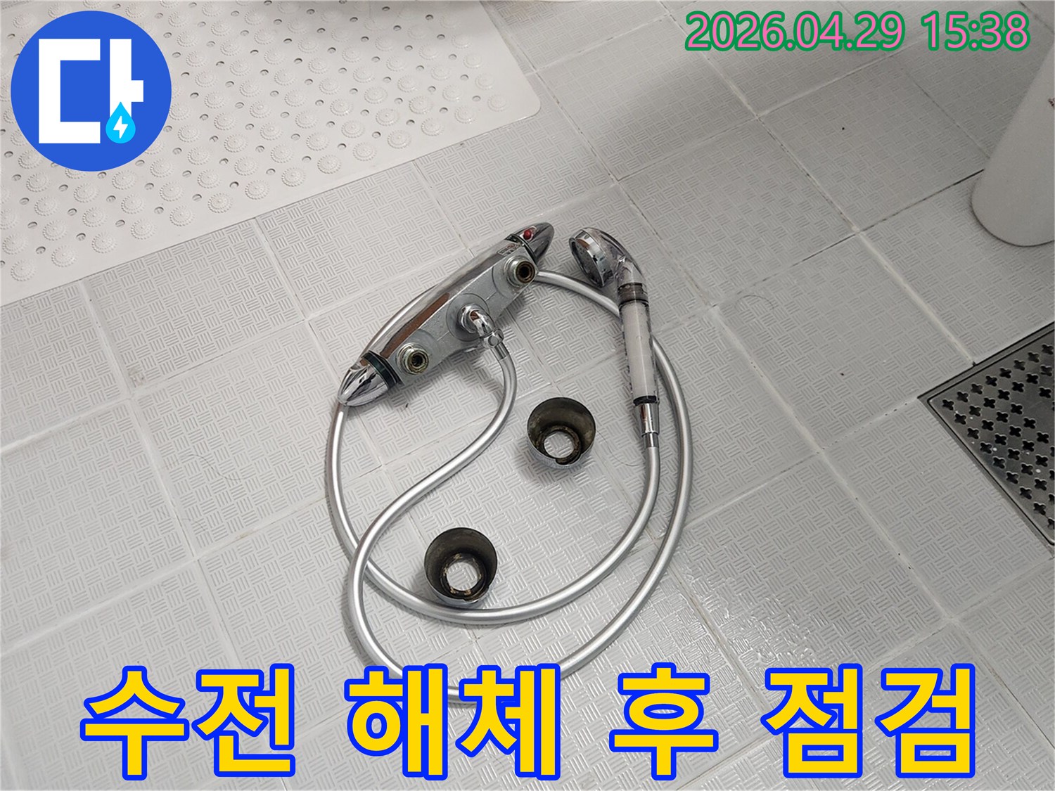 욕실 타일 바닥에-오래된-수전과-샤워기가-해체되어-놓여있으며-배관 누수 여부를-확인하는-모습입니다