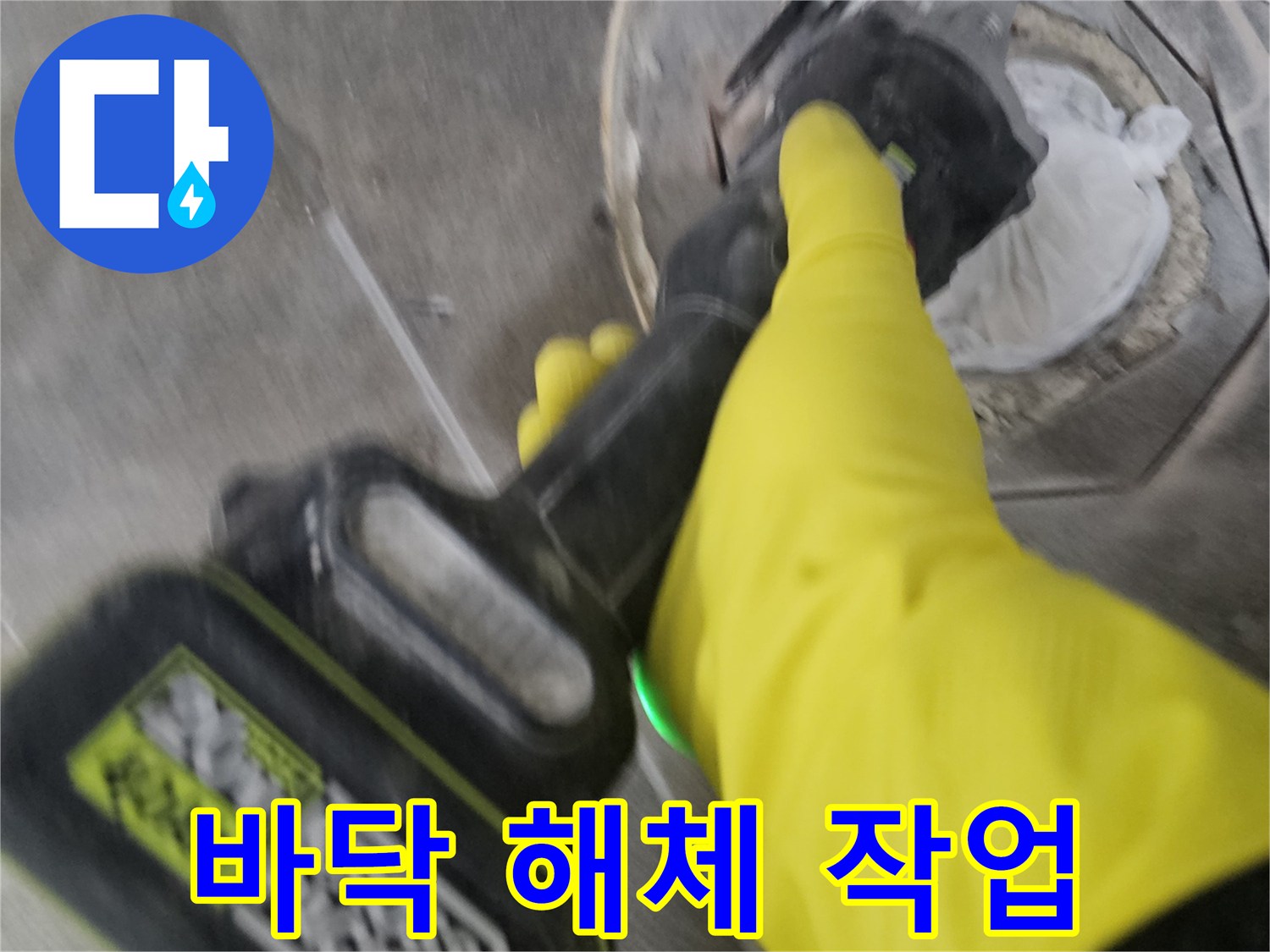 노란색 작업 장갑을 착용한-엔지니어가-전동 커팅기로-오수 배관 주변의 바닥을-조심스럽게 해체하는 장면입니다.