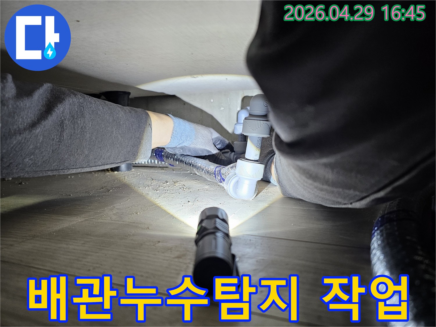 누수-탐지-전문가가-어두운-공간에서-배관-연결부를-확인하는-모습