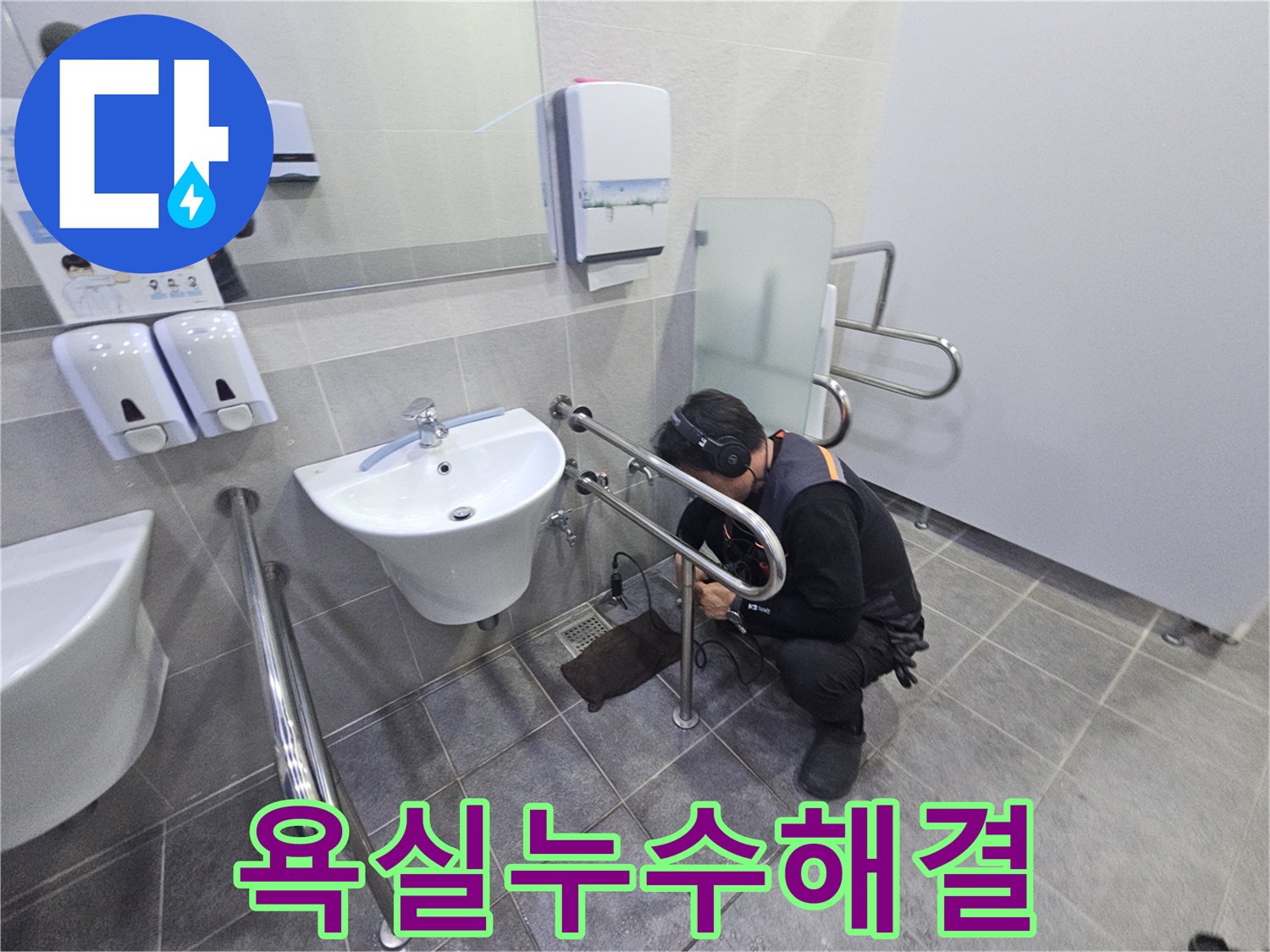 헤드폰을 착용한 기술자가-공용 화장실의 세면대 배관에서-미세한 누수 지점을 찾아내고 있습니다.