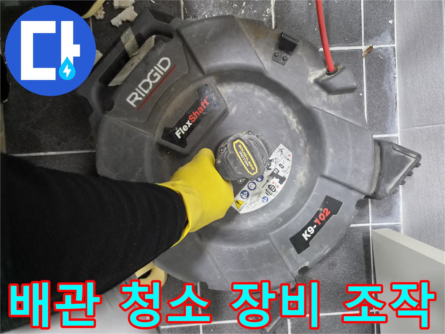 작업자가-노란색 고무장갑을 끼고-리지드 플렉스샤프트 K9-102 장비를 이용하여-배관 내부를 청소하는 장면입니다.