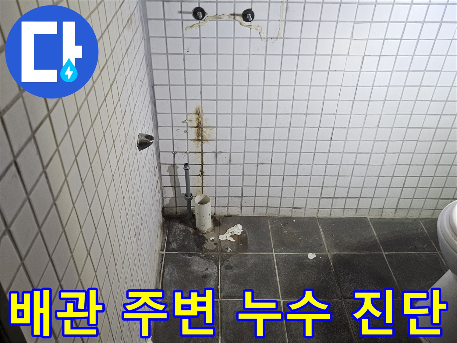 세면대 탈거 후-욕실 바닥에 노출된-하수 배관과-주변 타일의-누수 흔적을-정밀하게 검사하는-누수 전문가