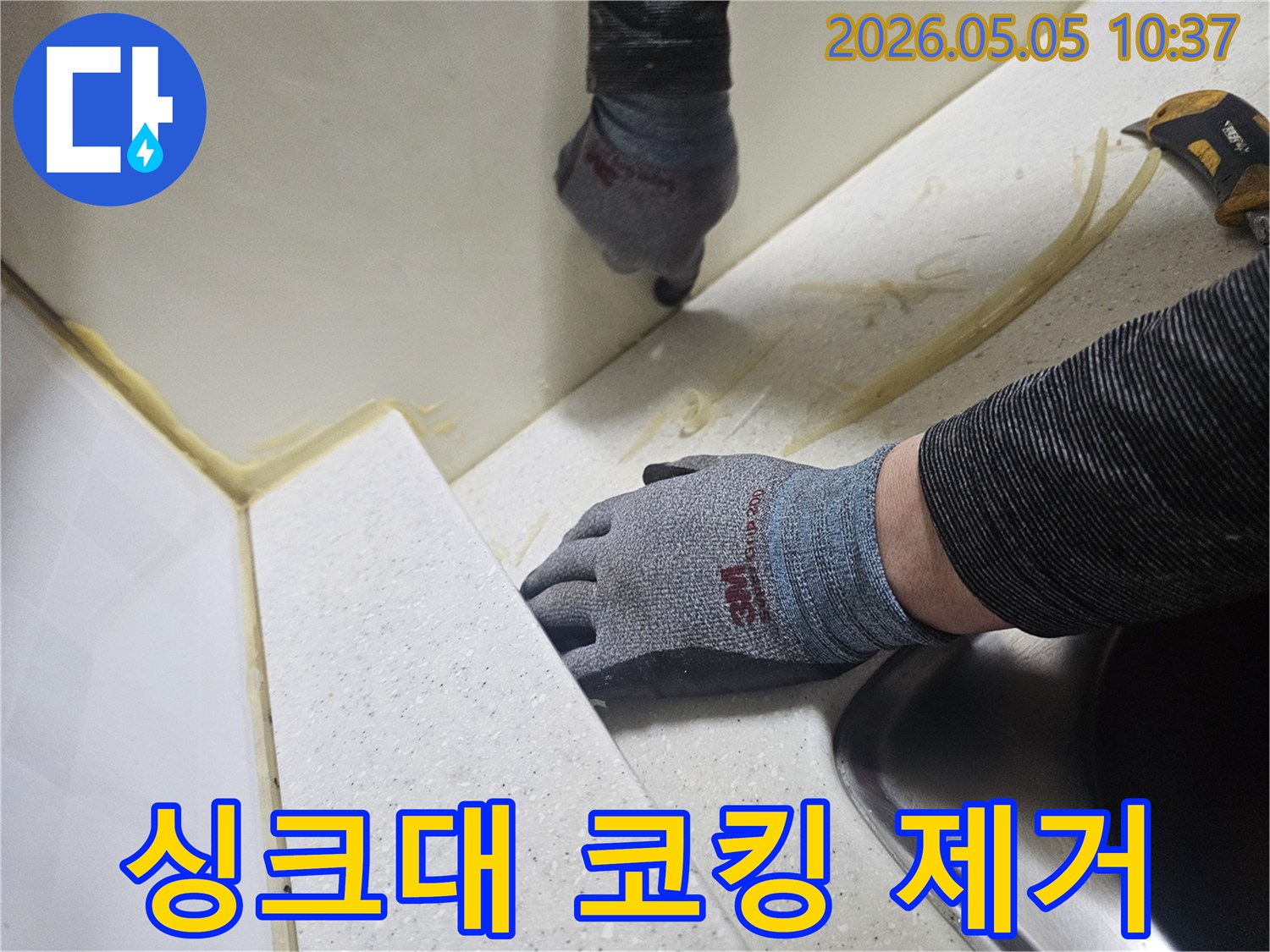 숙련된 기술자가 싱크대 주변의 오래된 코킹을 제거하고-새로운 방수 실리콘으로 재시공하기 위해-기초 작업을 진행하는 모습입니다