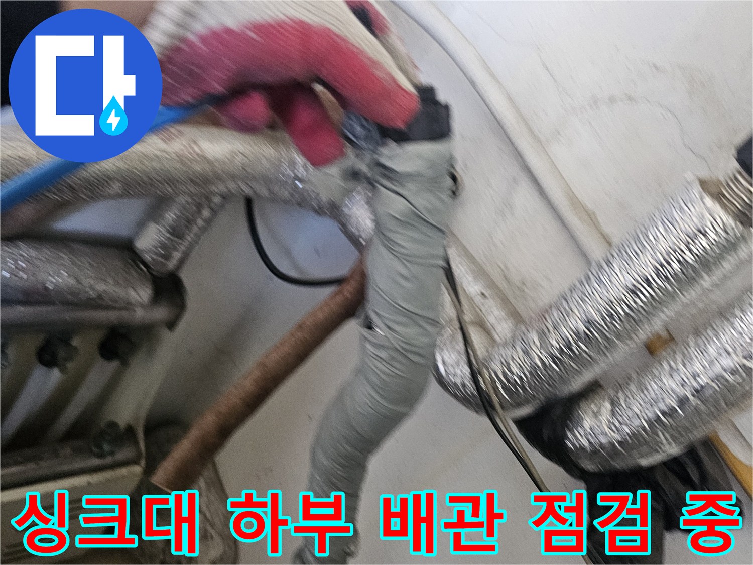 작업자가 장갑을 끼고-싱크대 아래쪽 배관 틈새를 확인하는 장면