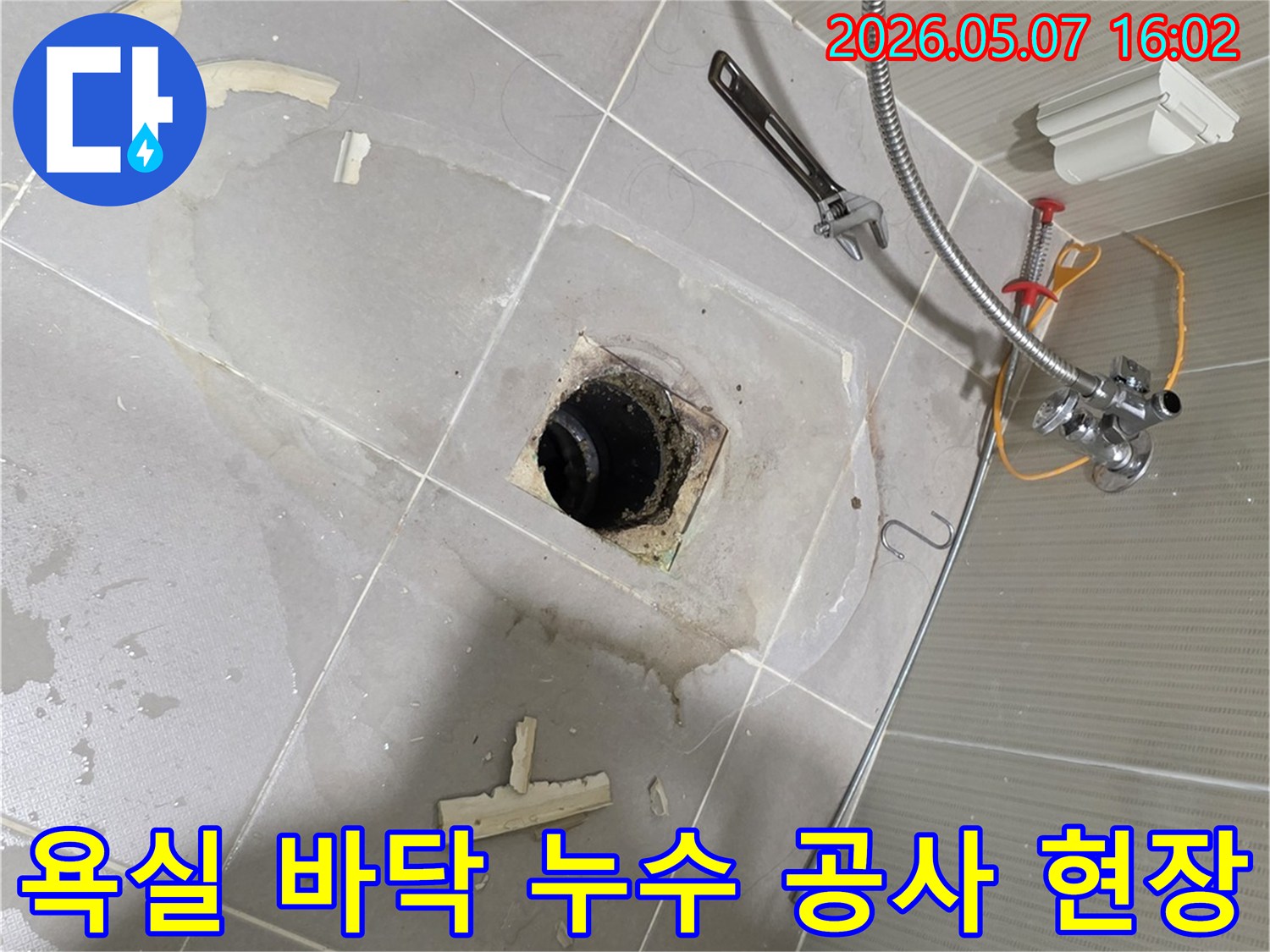 욕실 바닥 배수구 주변에서 진행되는 누수 탐지 및 보수 작업 현장-수도 배관과 공구들이 놓여있습니다