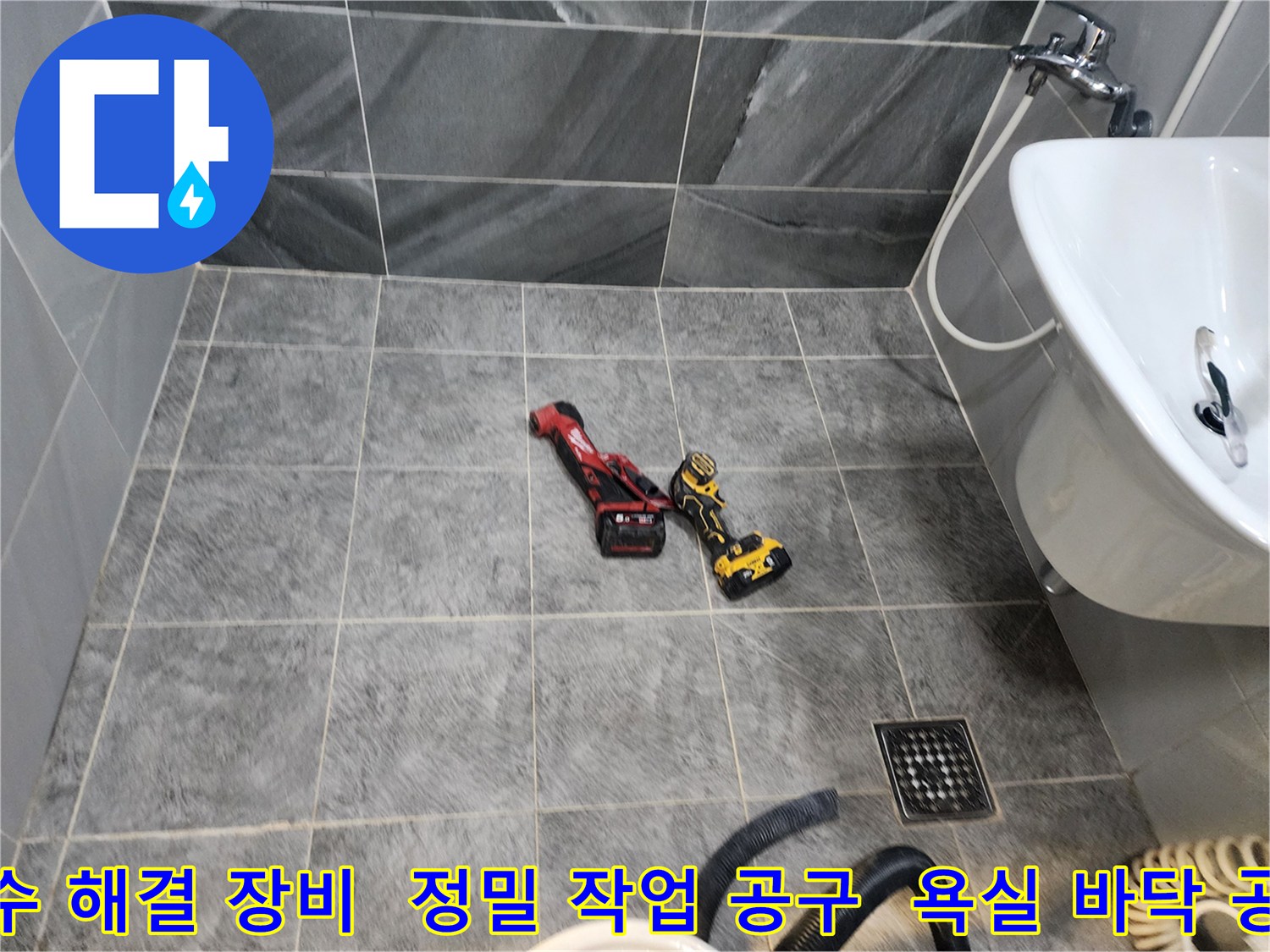 이 사진은 누수 탐지 작업을 위해-욕실 바닥에 놓인-전문 전동 공구들을 보여줍니다.
