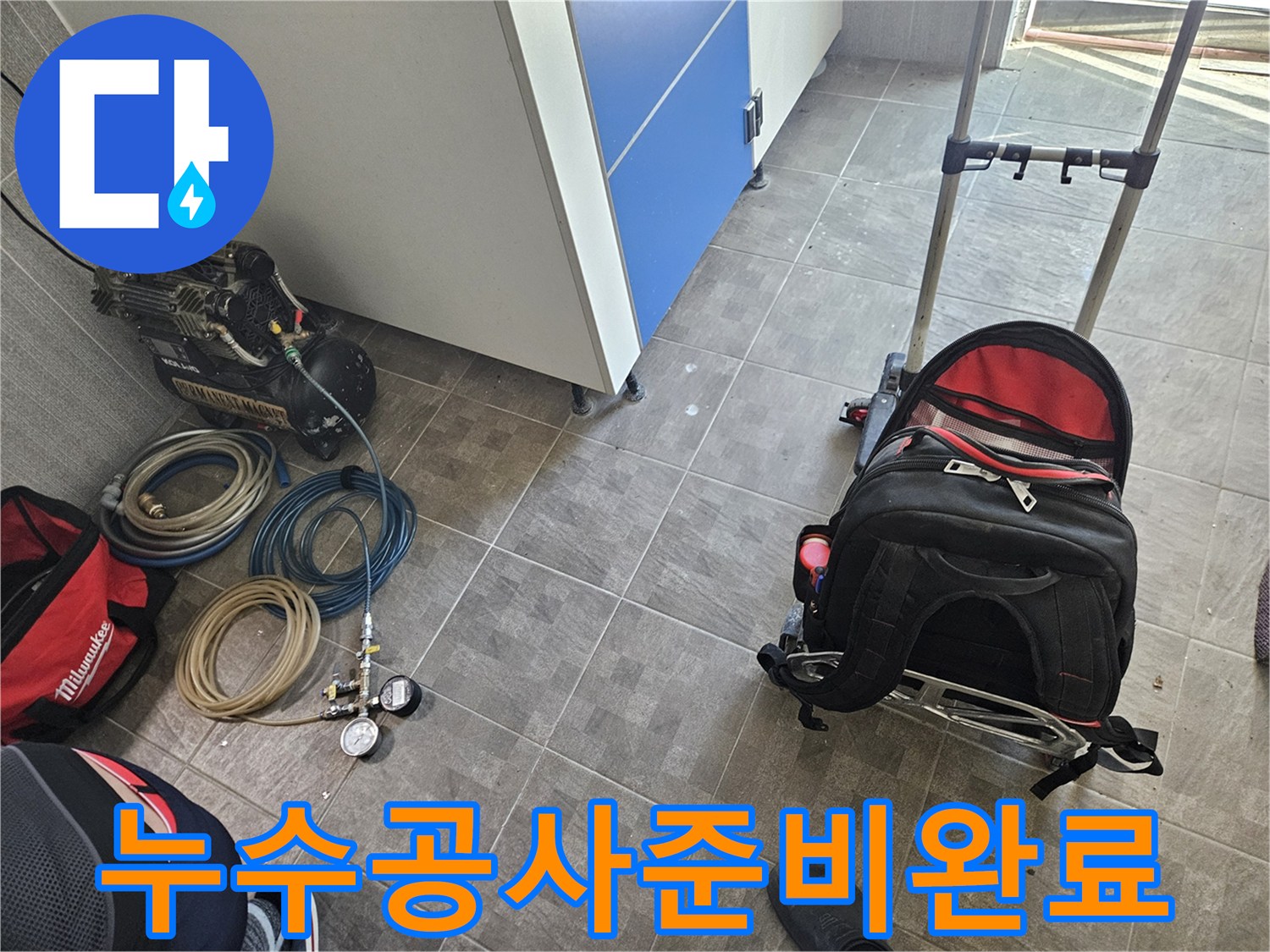 누수 공사를 위한 필수 장비인-콤프레셔와 압력 측정기가-작업 현장에 놓여 있는 모습