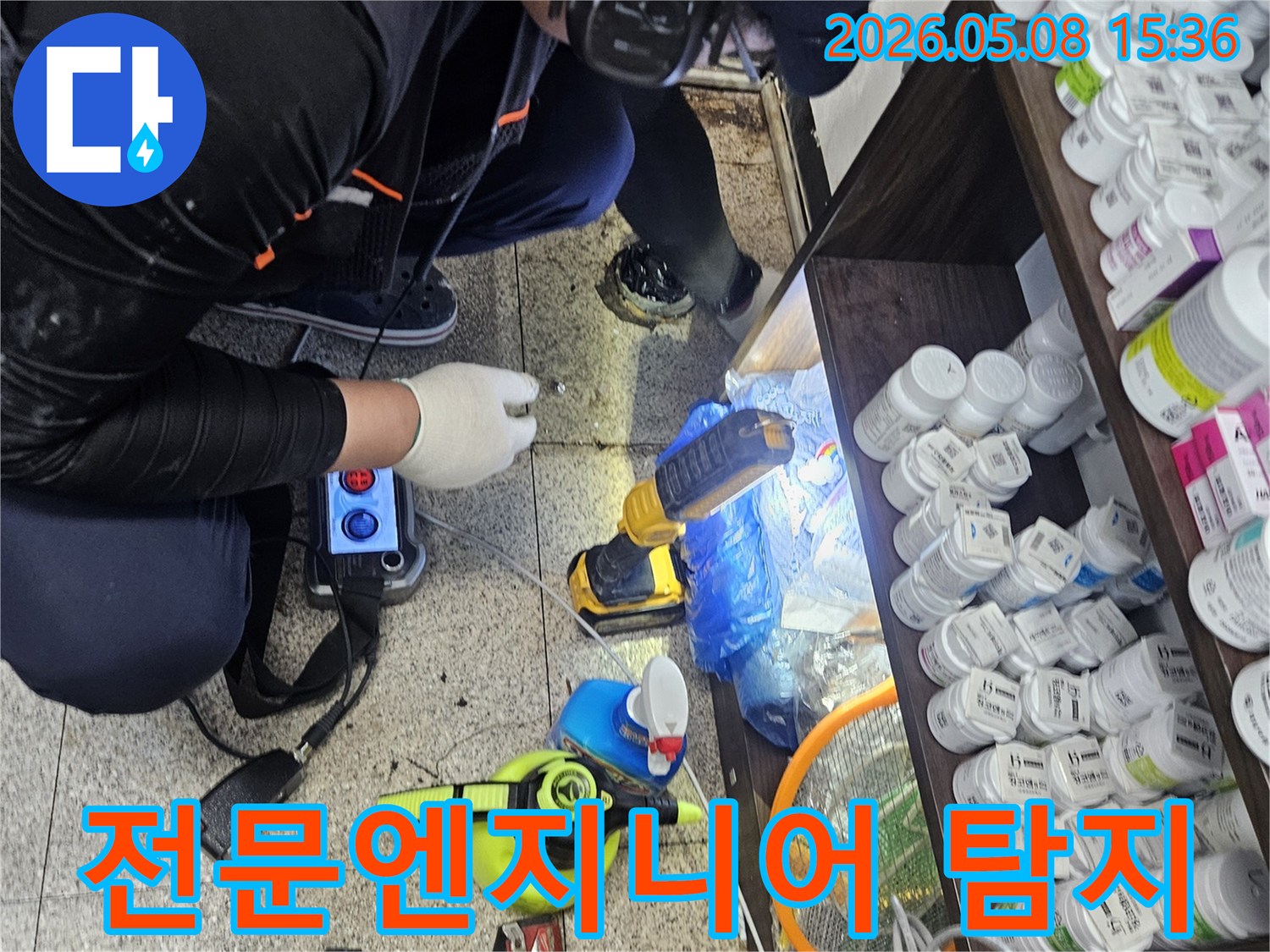 숙련된 누수 엔지니어가-싱크대 아래에서-청음 탐지 장비로-배관 누수 지점을 확인하는 장면