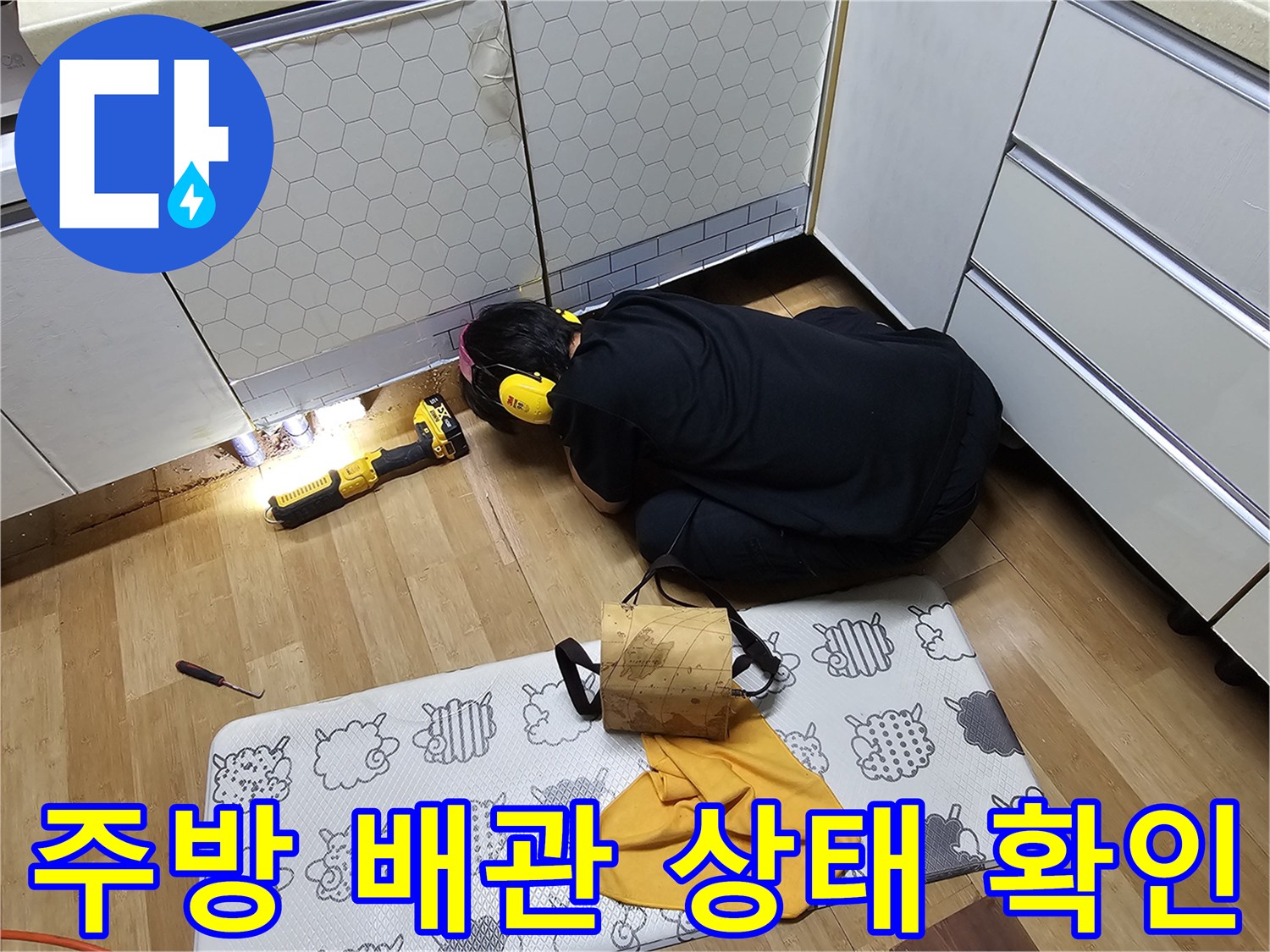 싱크대 아래 공간에서 배관 연결부를 점검하는 엔지니어의 작업 모습