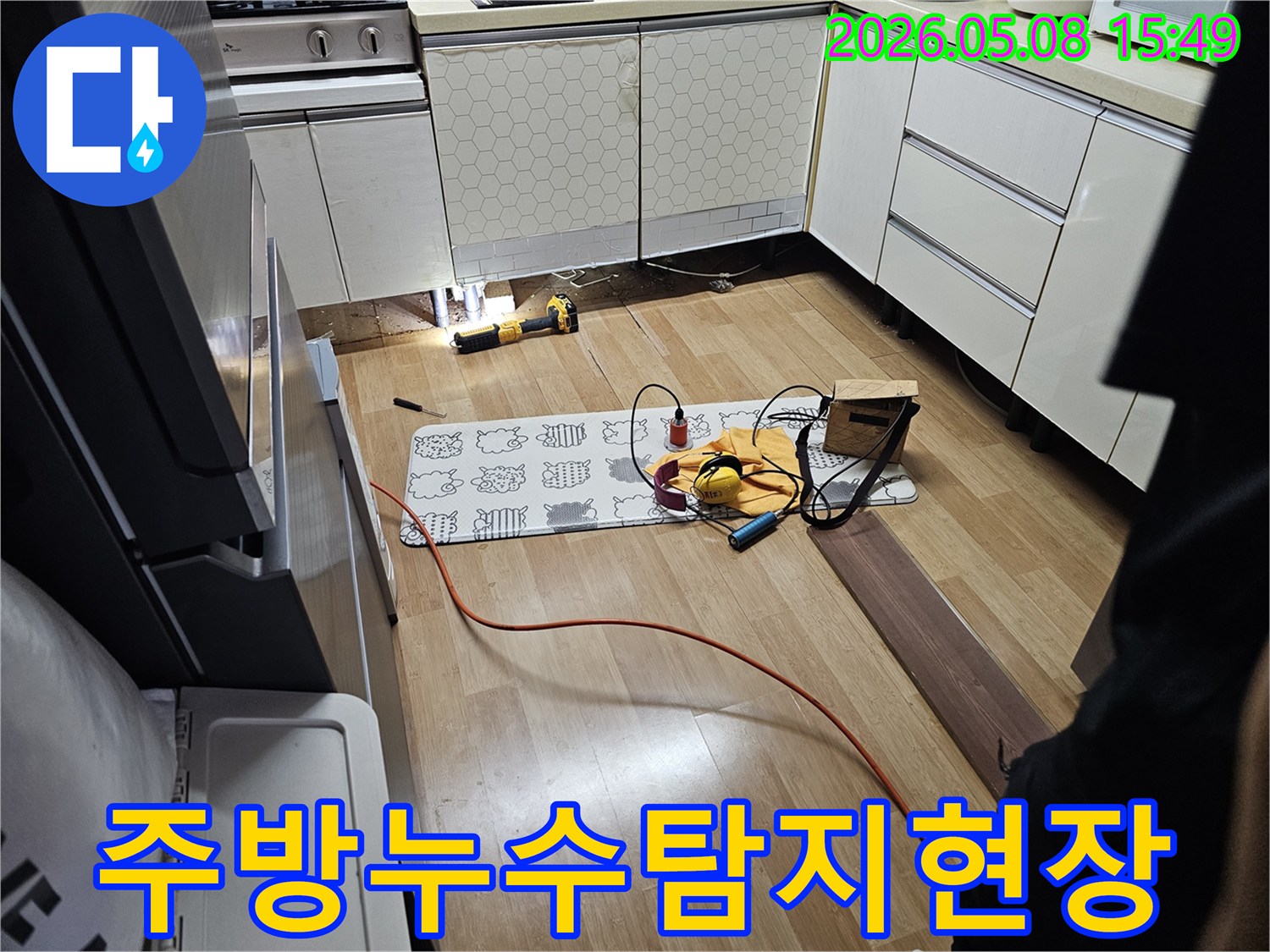 전문가가 주방 싱크대 하부에서-누수 원인을 찾기 위해-정밀 탐지 장비를 사용하는 모습