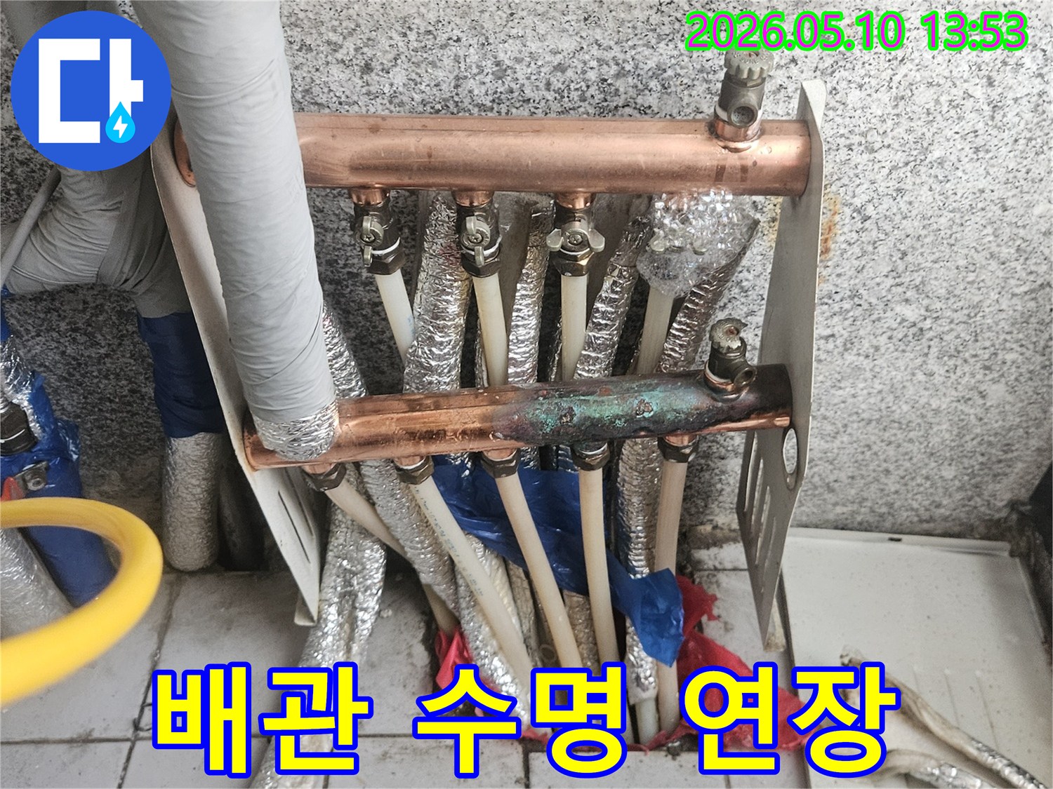 오래된 동파이프 난방 분배기가-부식되고-노후화가 진행된-모습을 보여주며-배관 수명 연장을 위한-관리가 필요함을 강조하는-현장 이미지입니다.