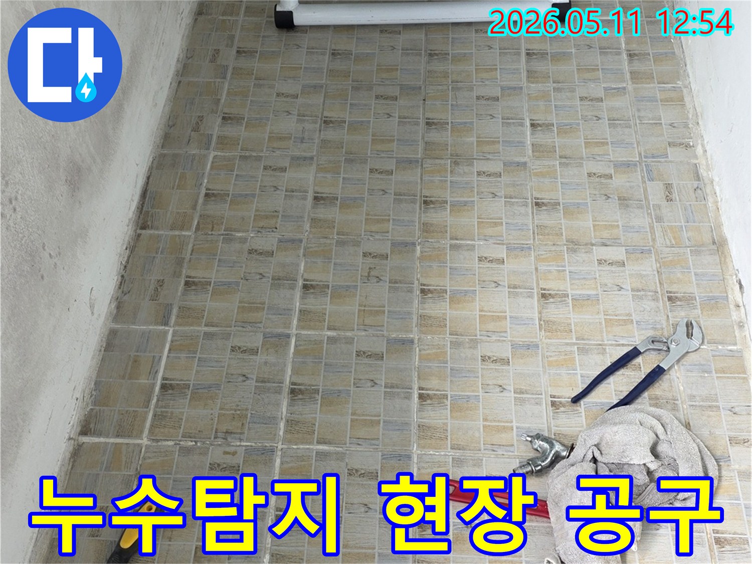 누수 탐지 현장에서-타일 벽면과-작업에 필요한 공구들이 놓여있는 모습