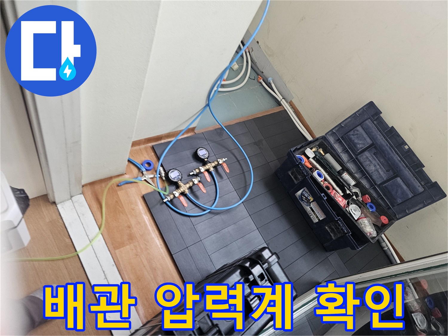 타일 바닥 위에 배치된 공압 테스트용 게이지와 호스 연결 부위