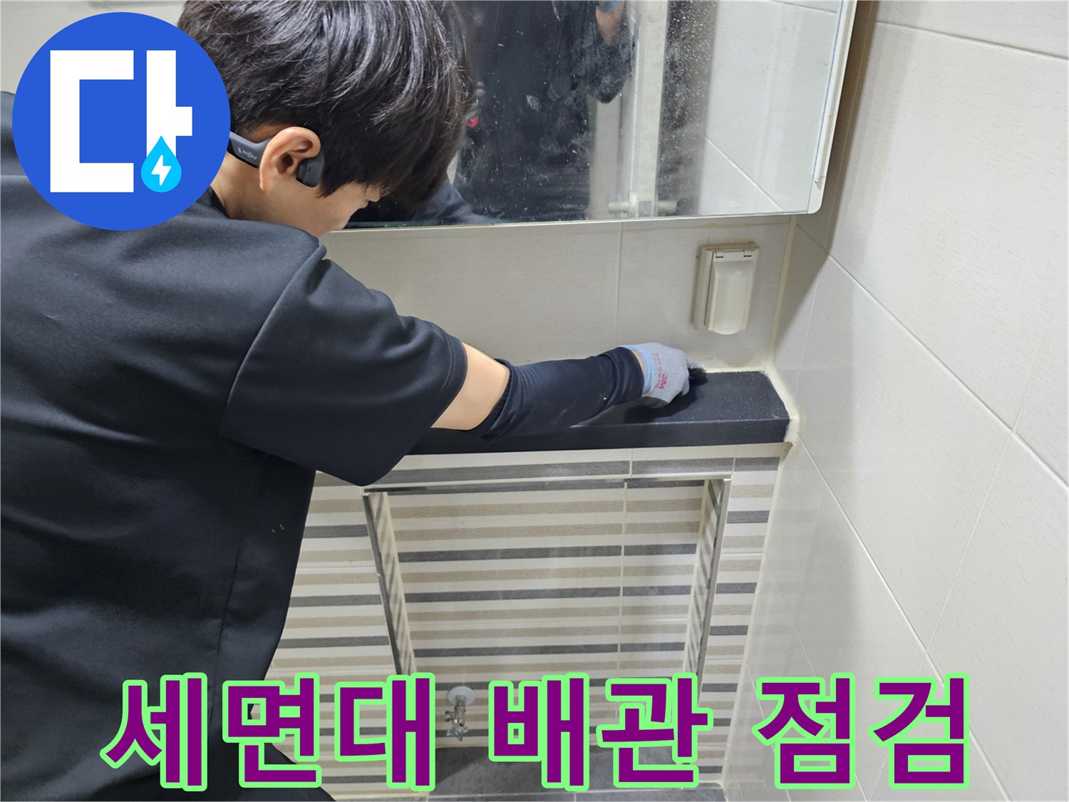 작업자가 세면대 하단 배관의 연결부를 직접 만져보는 장면