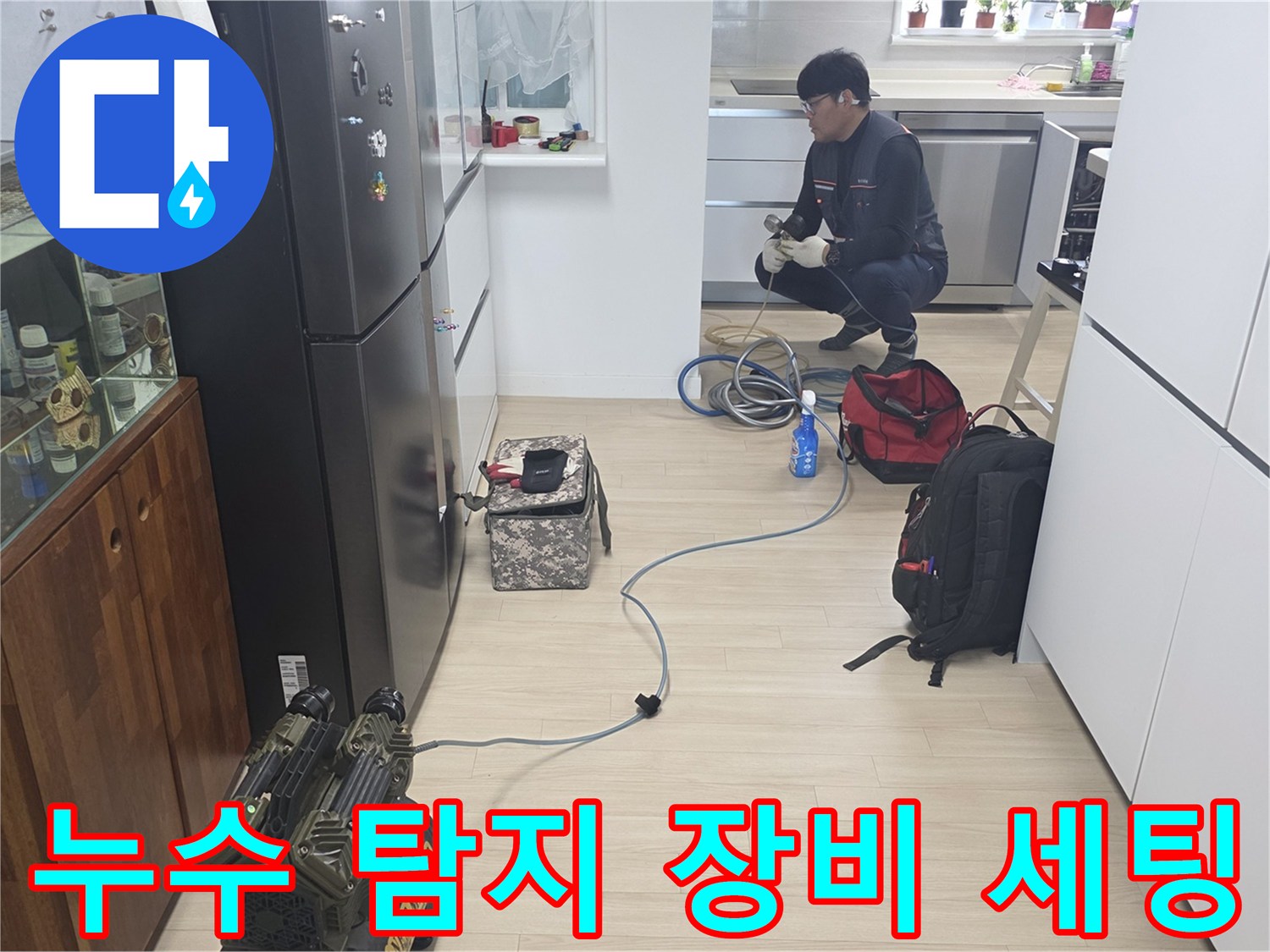 주방 싱크대 근처 바닥의 누수 지점을 찾기 위해 가스 탐지기와 청음기를 배치하는 작업 현장입니다.
