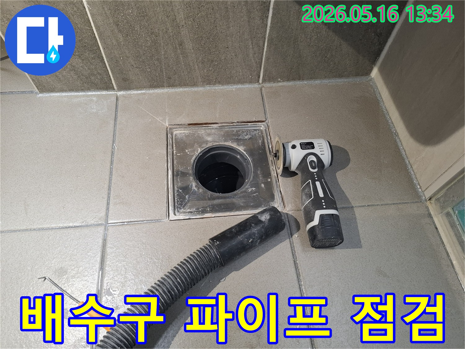 누수 엔지니어가 욕실 배수구 주변의 배관 누수를 점검하고-보수 작업을 준비하기 위해-전동 공구로 표면을 정리하는 중입니다