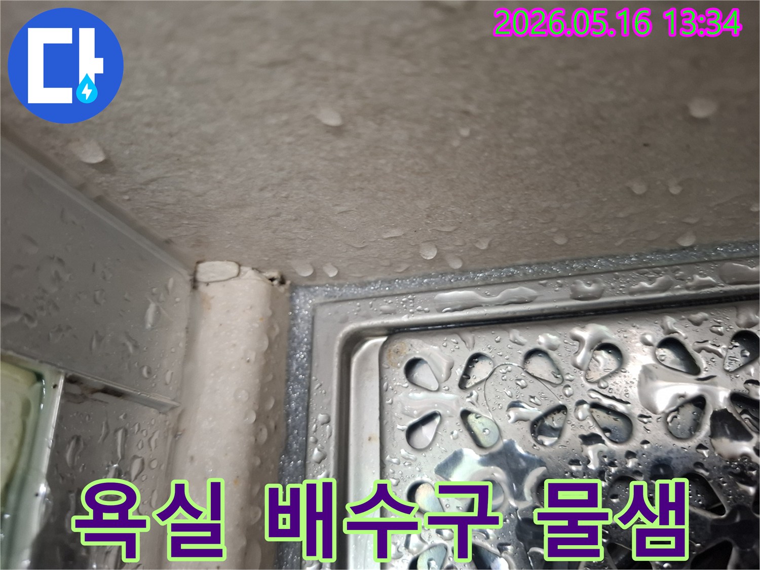 사진은 욕실 배수구 주변에 물이 고여있는 모습을 보여주며-누수가 발생하고 있음을 나타냅니다.
