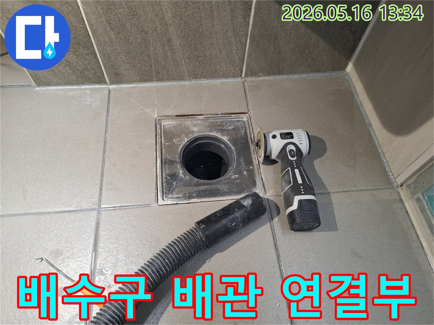 전문 엔지니어가 욕실 배수구 주변의 배관 연결부 누수를 점검하고-보수 작업을 준비하기 위해-전동 공구로 표면을 정리하는 중입니다