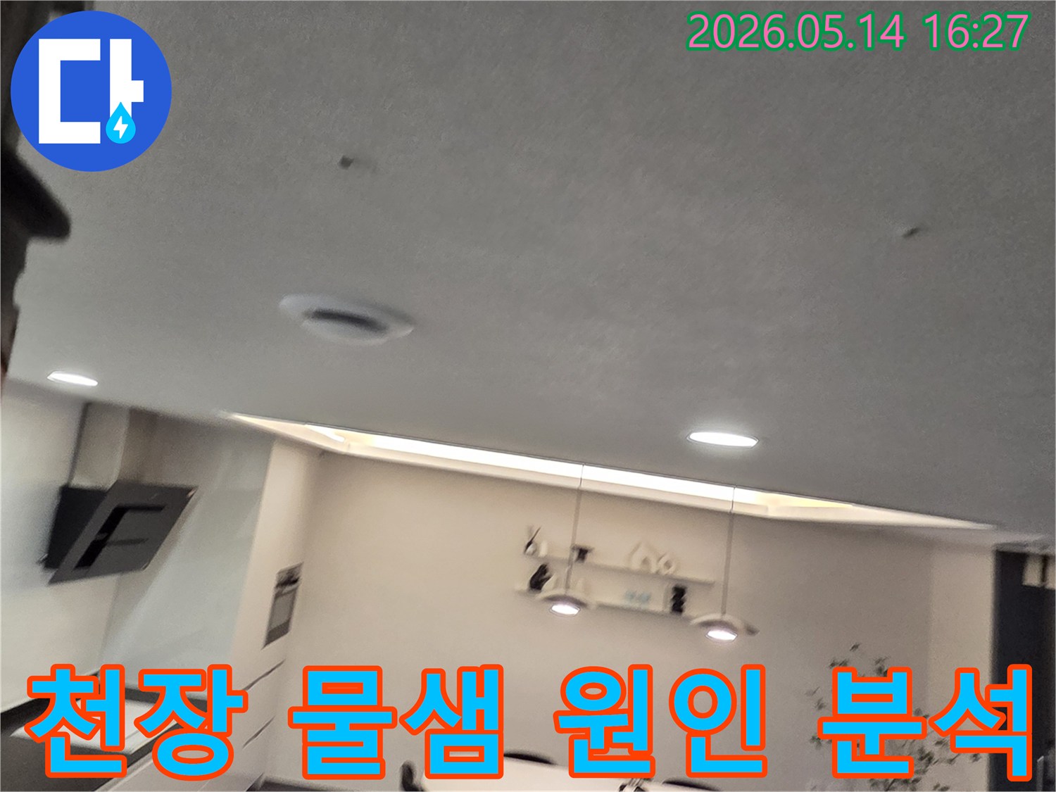 이 이미지는 주방 천장에 나타난-작은 물 얼룩과-환기구를 보여주며-천장 물샘 현상의-근본적인 원인 해결이-필요함을 시사합니다