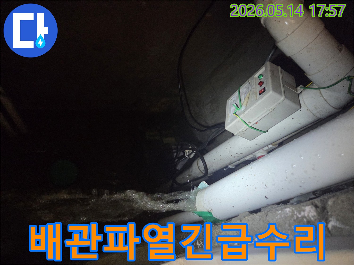 어두운 지하 공간에서-파이프에서 물이 강하게 뿜어져 나오는-지하 배관 파열 현장을 보여주는 사진입니다-전기 제어 박스와 배관들이 함께 보입니다.