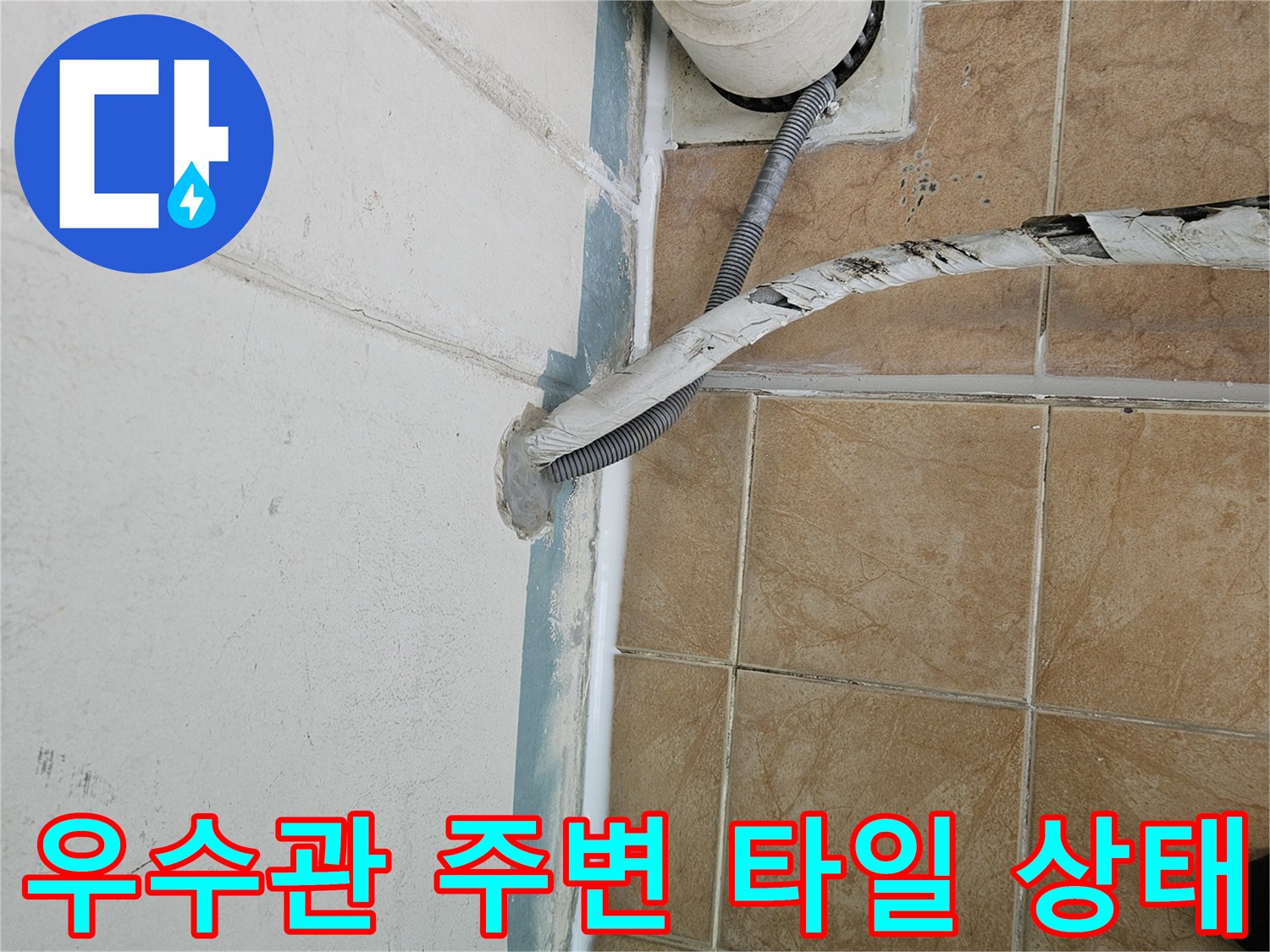 베란다 우수관 하단 배관과 벽면 타일 사이의 벌어진 틈을 보여줍니다.