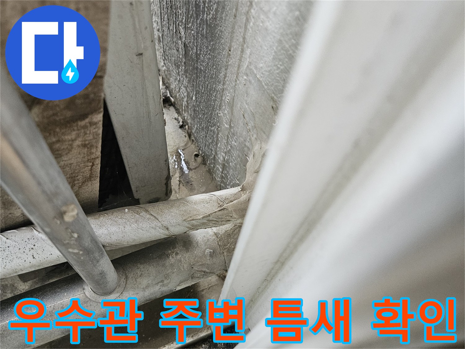 아파트 베란다 우수관 연결 부위의 미세한 틈새와 습기 상태를 점검하는 모습