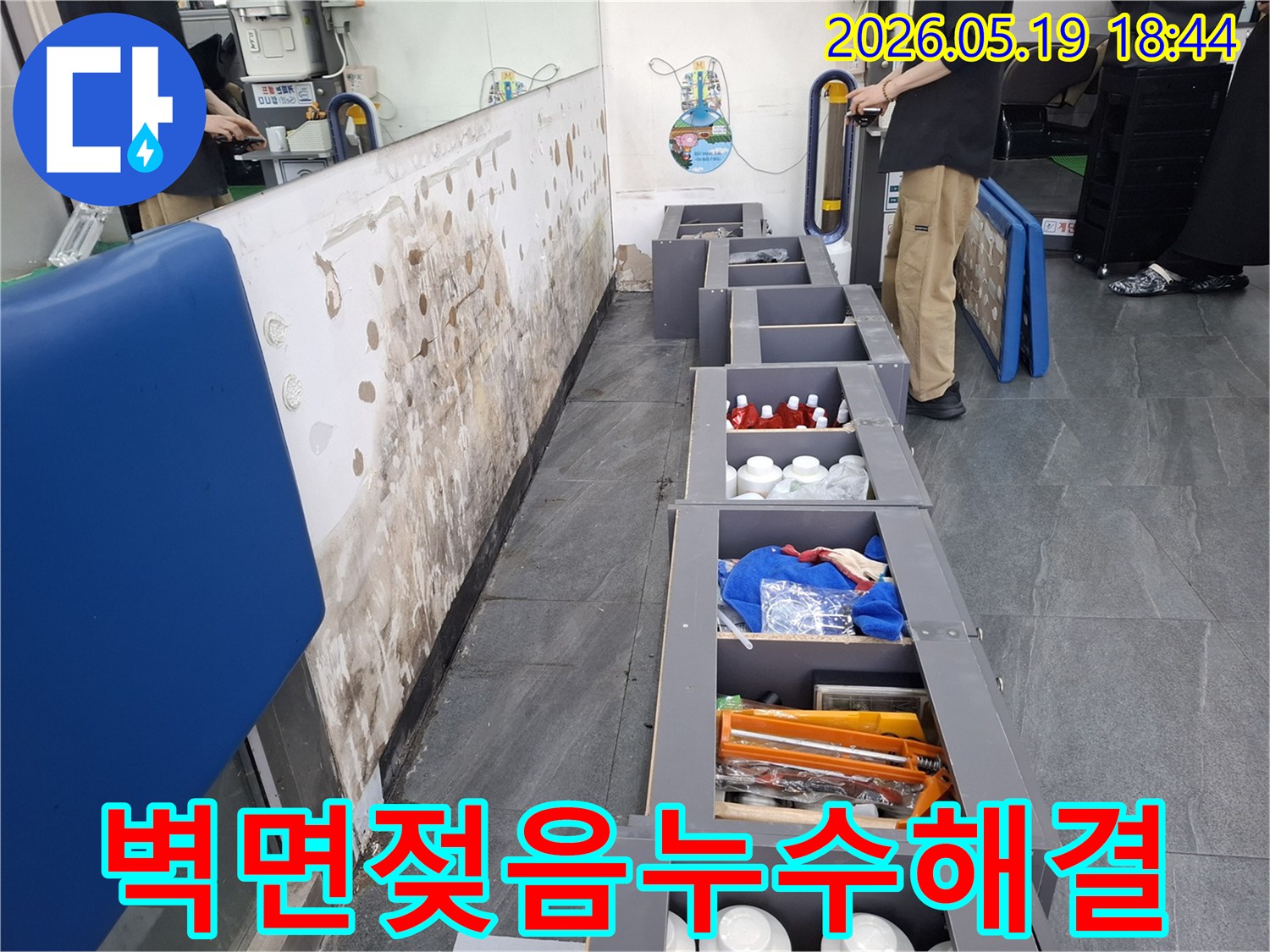 누수로 인해 젖어버린 벽면과-그 주변의 정리된 수납장-그리고 누수 해결을 위해 방문한 엔지니어의 모습