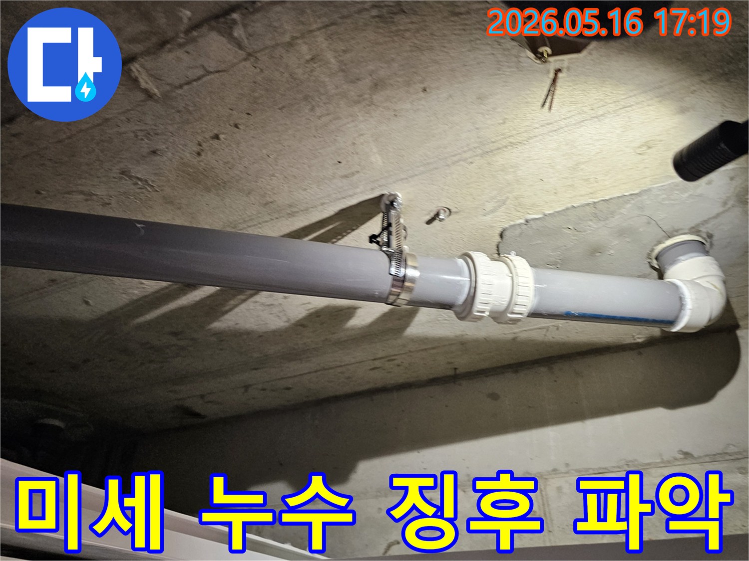 천장 배관이 드리운 그림자 주변에서-미세한 습기나 물방울로 인한-표면 변화를 감지하려는-전문가의 예리한 시선