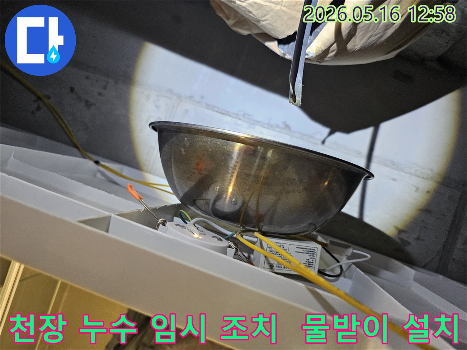 천장에서 물이 새는 상황을 임시로-스테인리스 볼로-받아내는 모습과-주변 전선 및-조명 부품