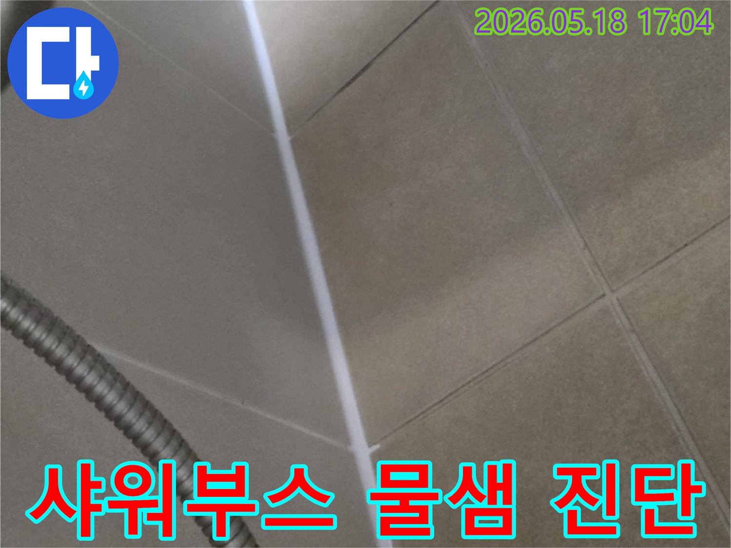 샤워부스 바닥과 벽면의 연결 부위-물샘 가능성을 진단하기 위해-타일과 줄눈 상태를 면밀히 관찰하는 모습입니다