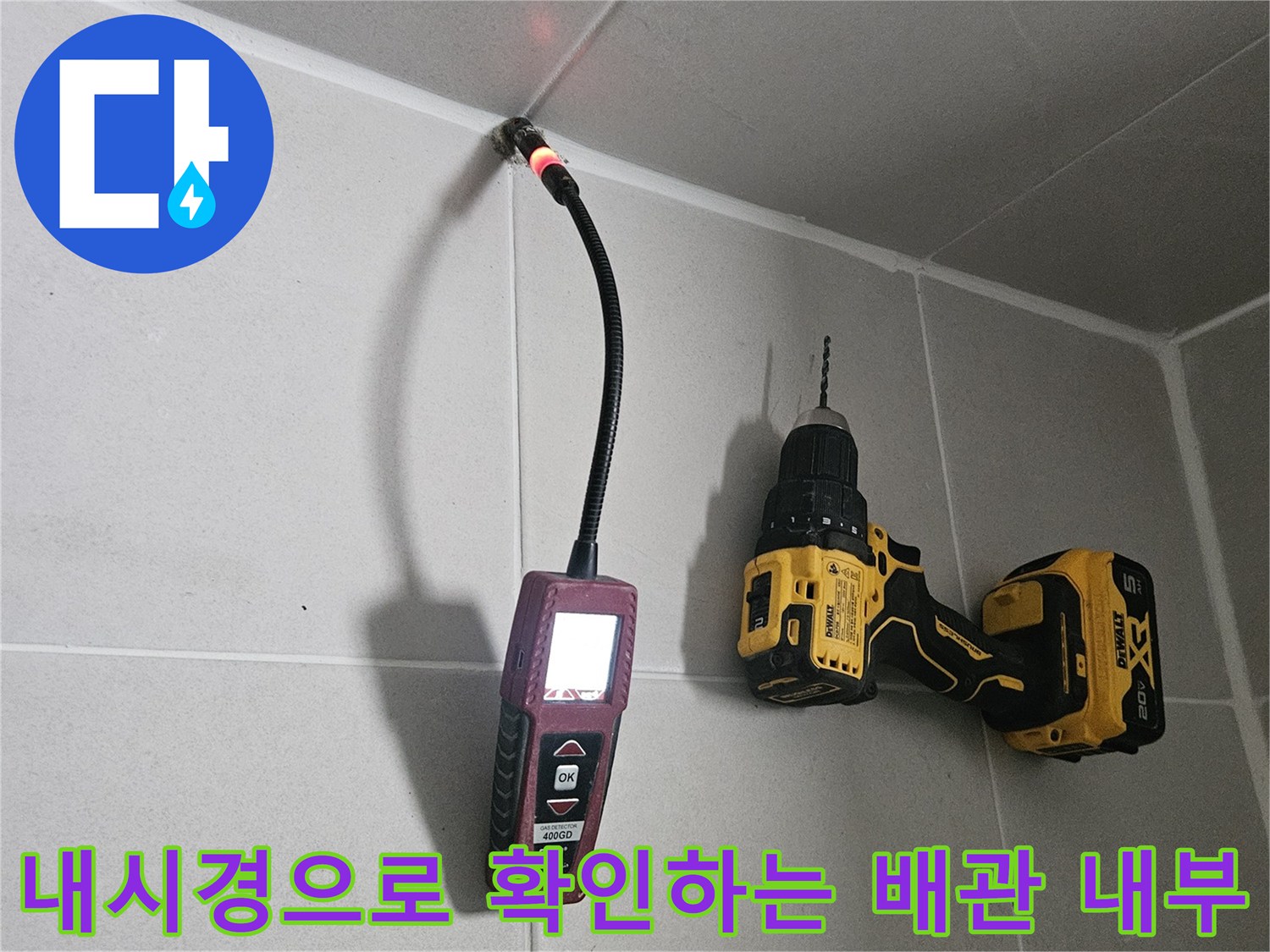 타일 틈 사이로 들어간 내시경 카메라와 현장에 준비된 전동 드릴의 모습입니다.