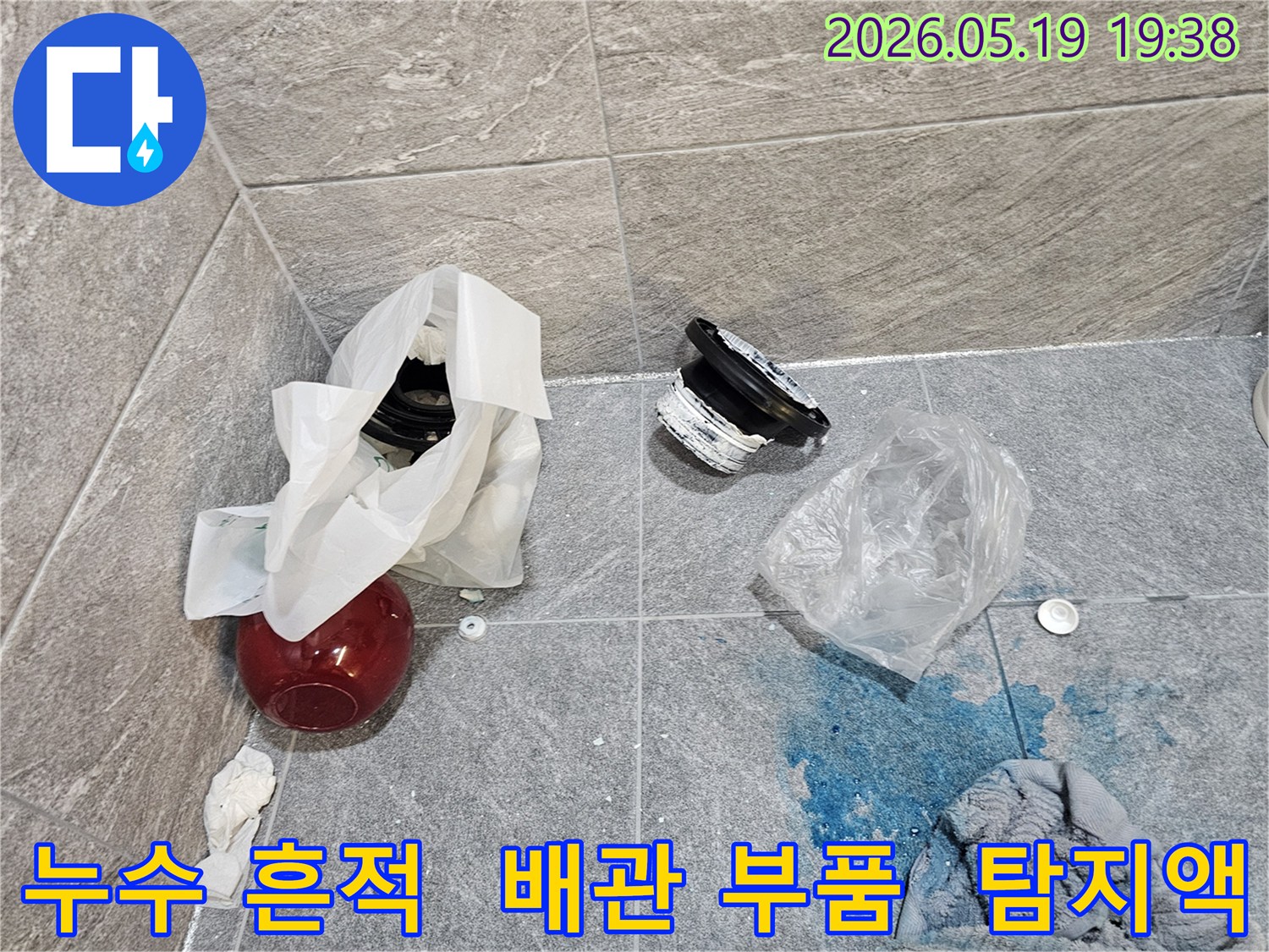 누수 탐지 현장에서-파란색 탐지액이 바닥에 묻어 있고-주변에는 해체된 배관 부품들이 놓여 있습니다
