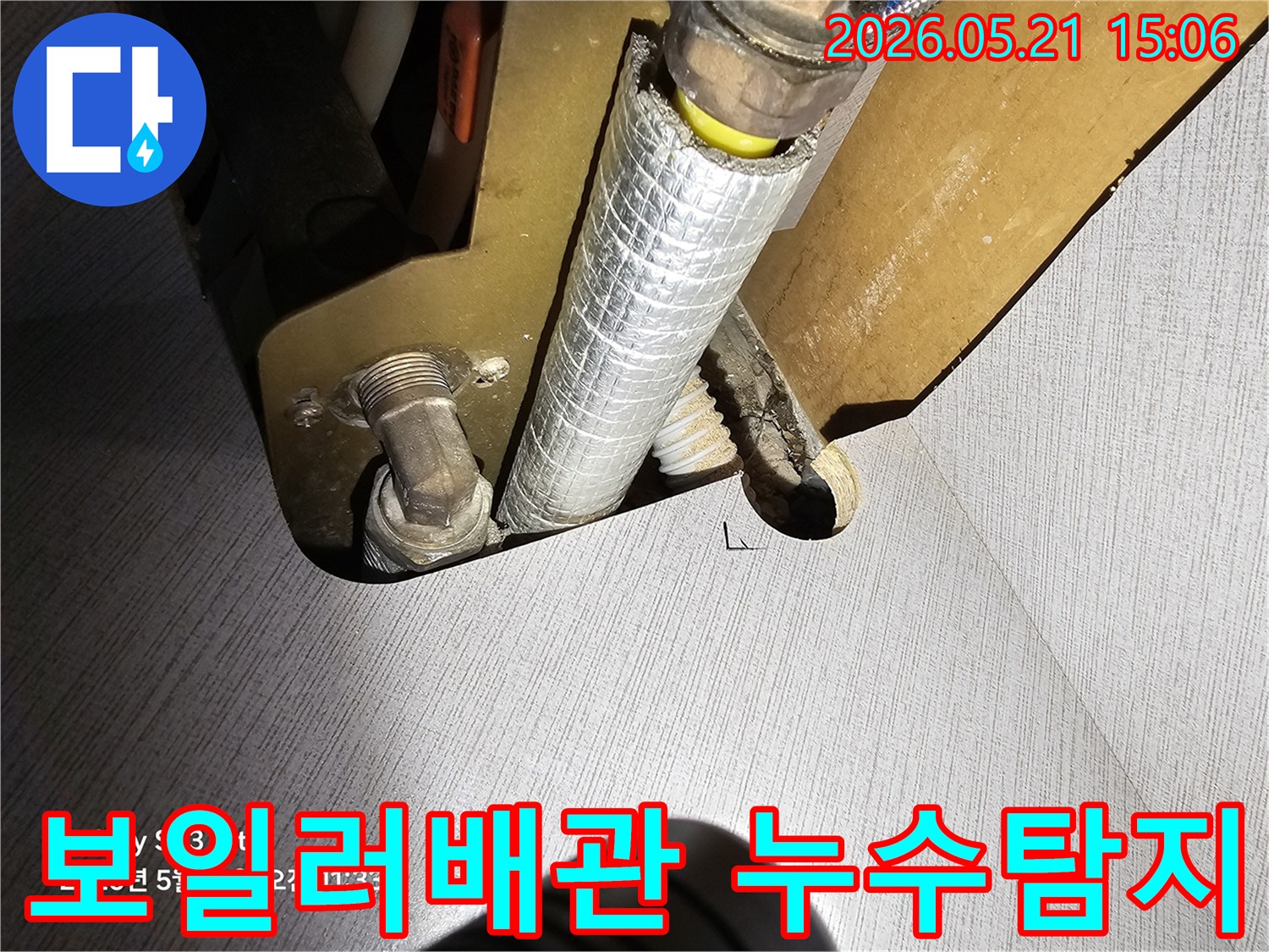 이 이미지는 주택 내부의 보일러 배관 연결부에서 발생한 누수 지점을 정밀하게 탐지하는 과정을 보여줍니다-전문가가 누수 원인을 파악하기 위해 면밀히 살피고 있습니다