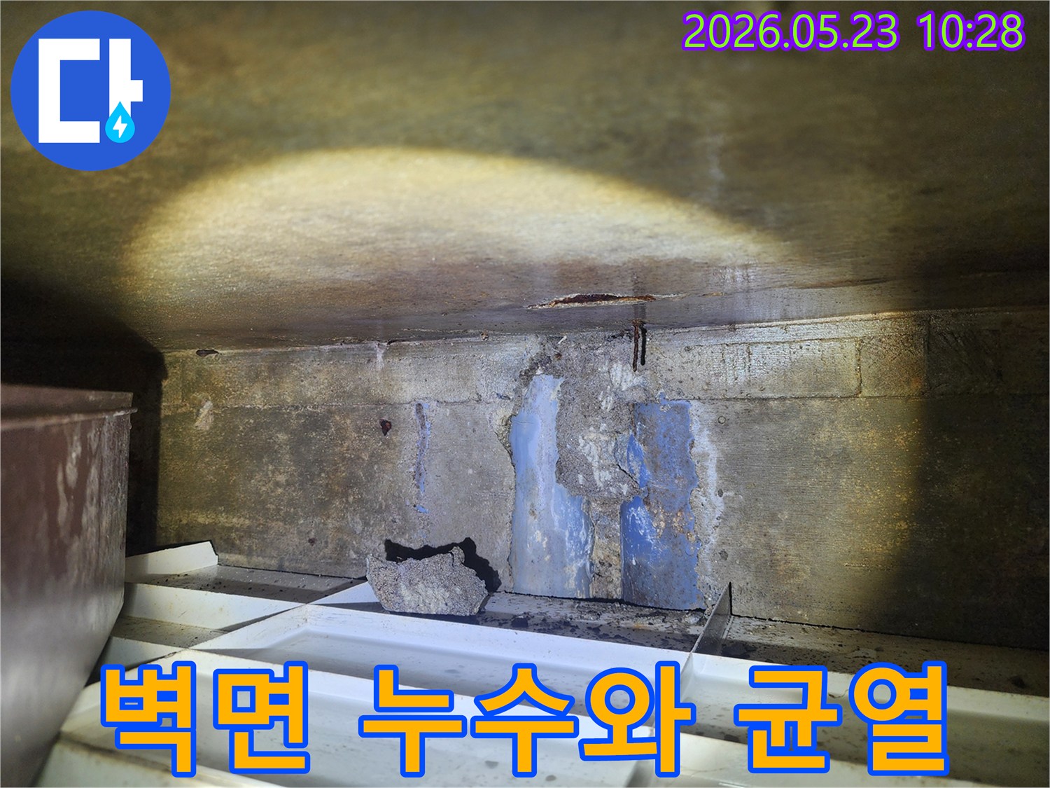 손상된-콘크리트-벽면에서-물이-새고-있으며-바닥에-물받이가-설치된-누수-현장