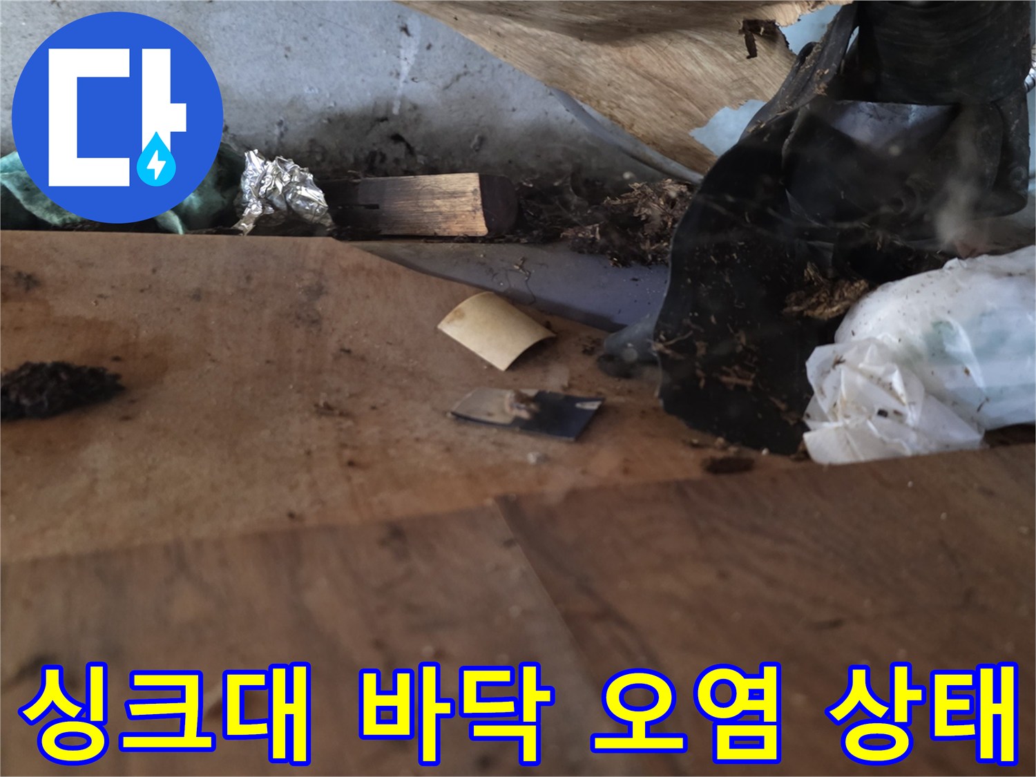 싱크대 하부장 바닥의 나무판이 습기로 인해 변색되고 곰팡이가 발생한 모습입니다.