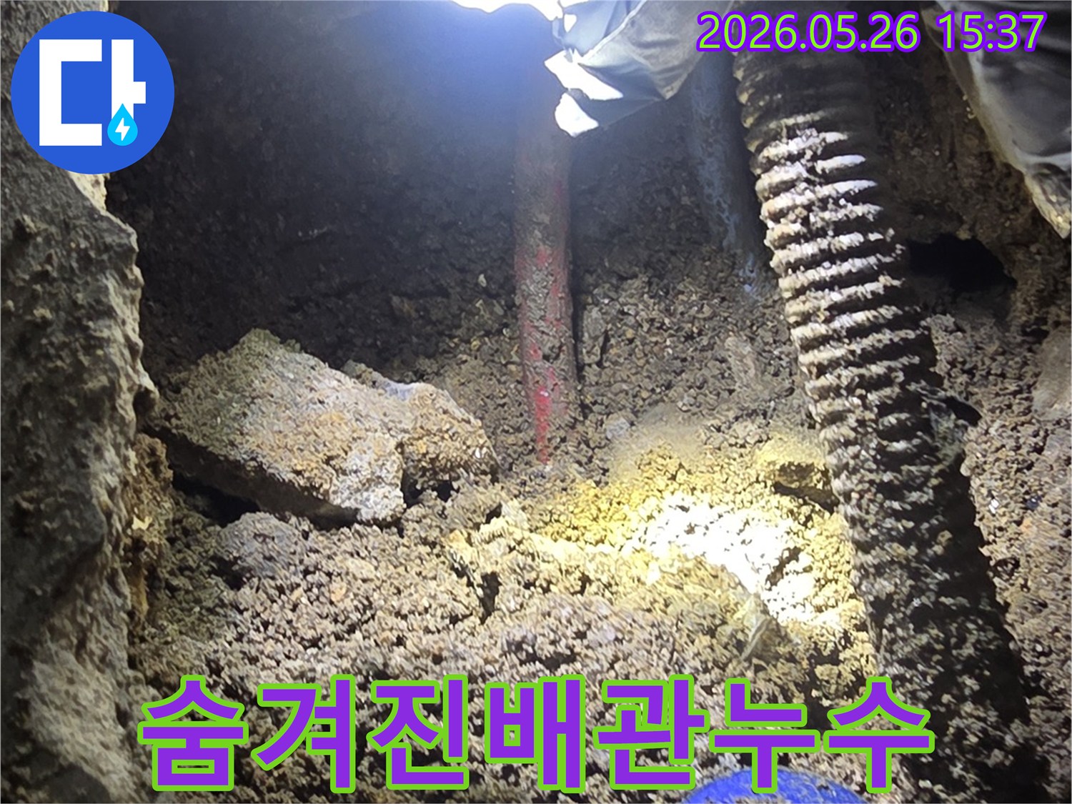 누수-전문가가-어두운-굴착-현장에서-손전등으로-숨겨진-배관-누수-지점을-정밀하게-확인하는-과정