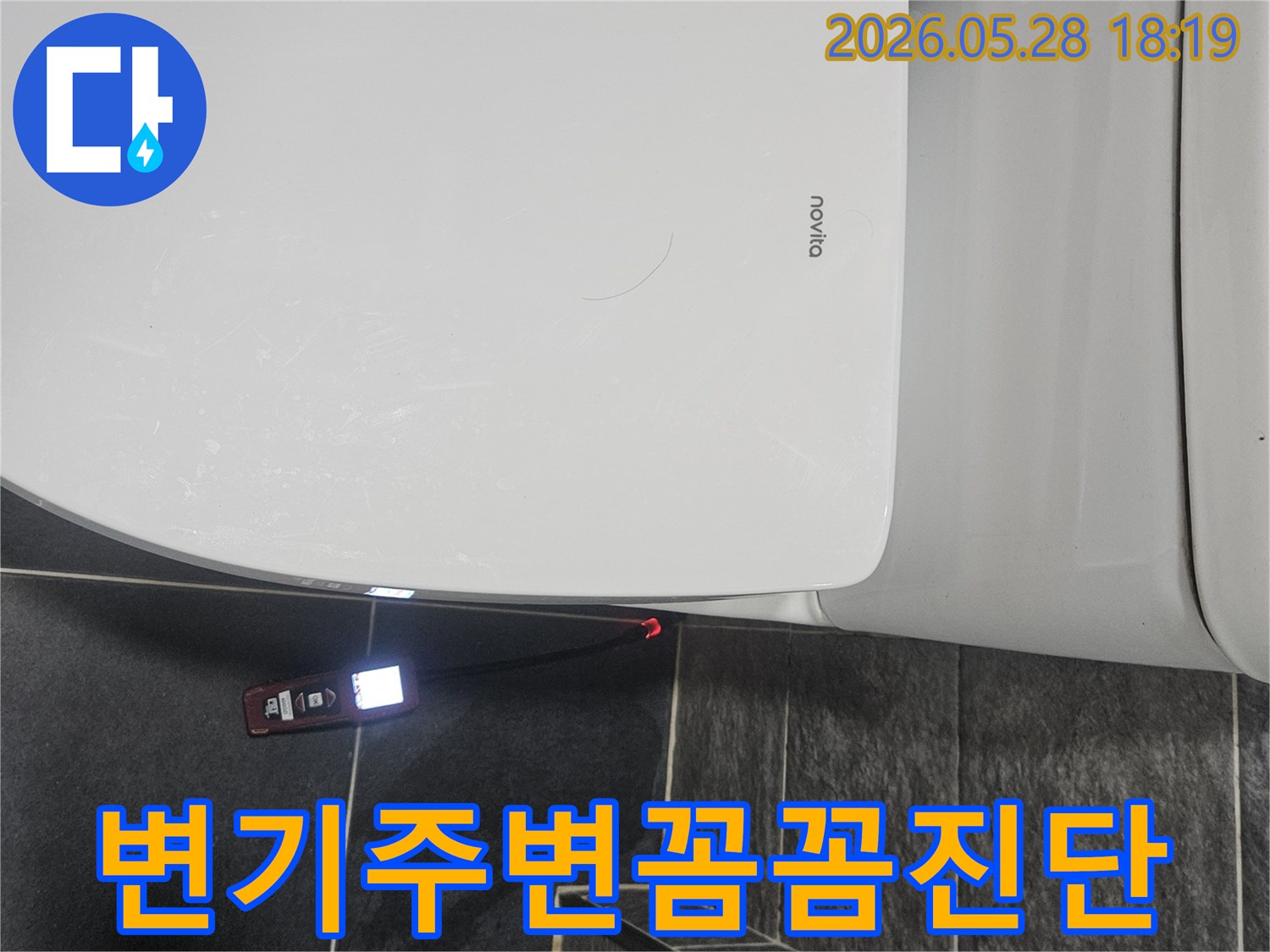 화장실 변기 옆-어두운 바닥 타일 위에서-누수 탐지기가-빨간색으로-누수 지점을 표시하고 있습니다.