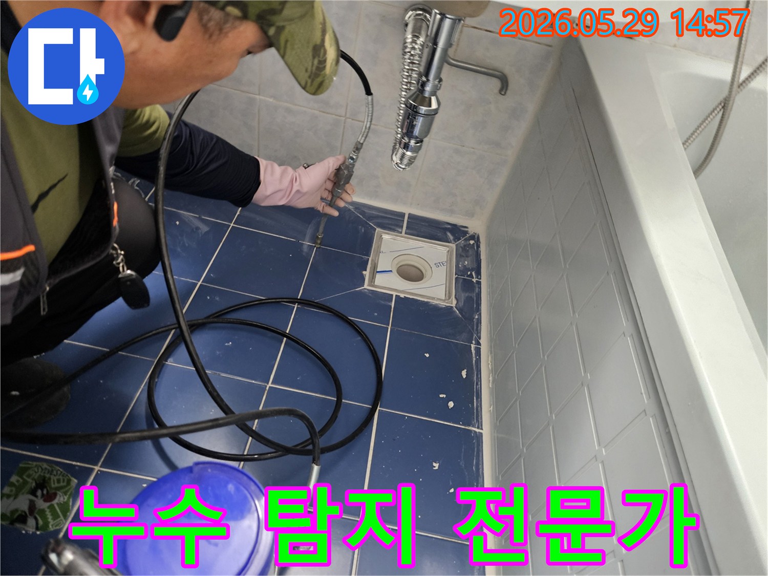 숙련된 누수 탐지 전문가가 욕실 바닥 배수구에 특수 장비를 삽입하여 화장실 누수 원인을 정밀하게 탐지하는 모습입니다-전문가의 섬세한 손길이 느껴집니다