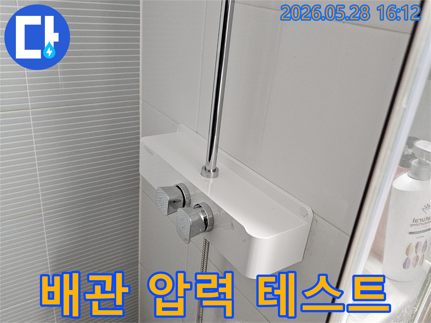 이 사진은-욕실 샤워부스-상단에 설치된-수전과-배관 연결-지점을-면밀히-관찰하는-모습입니다.